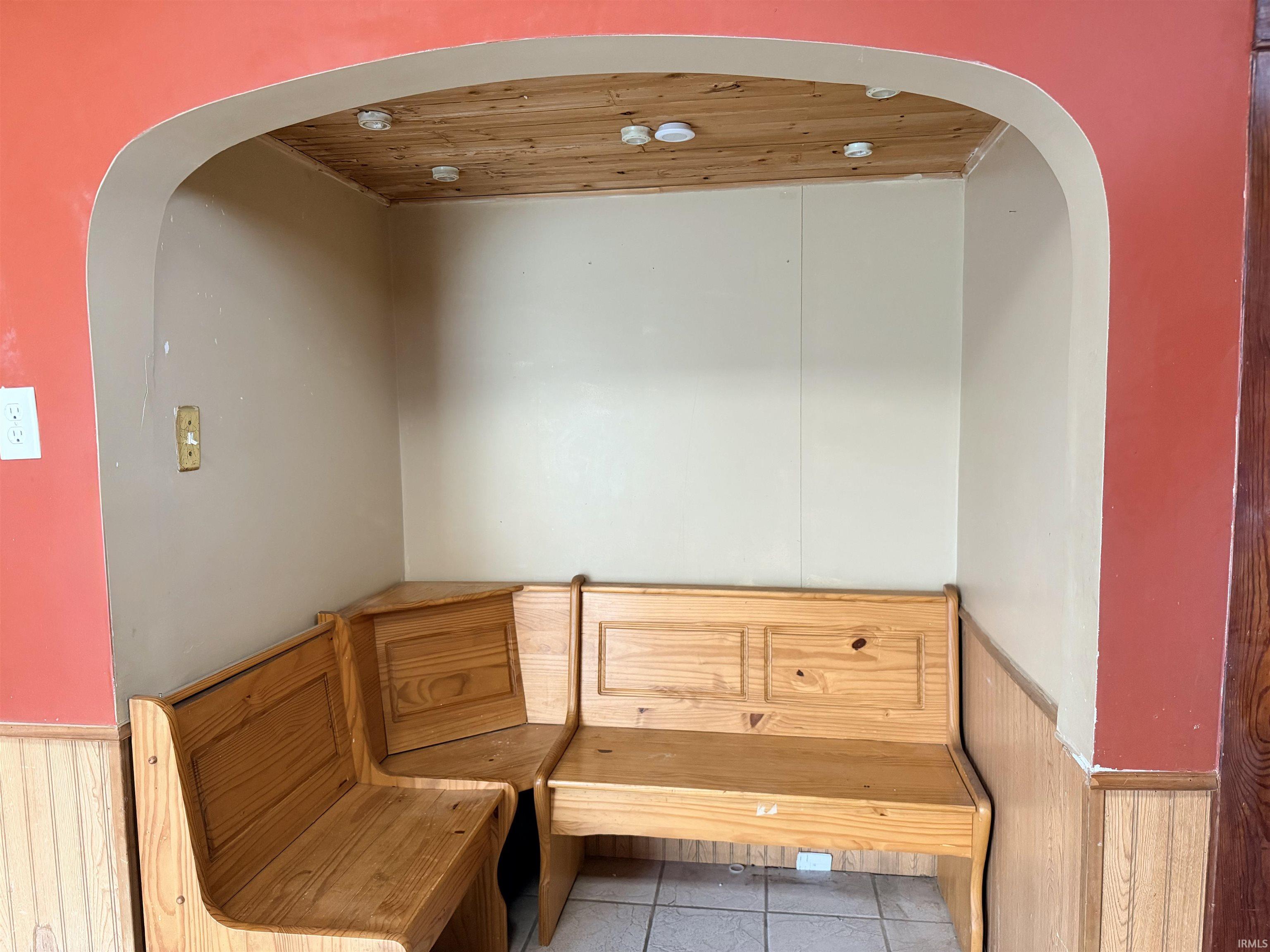 Interior space featuring a wainscoted wall, wooden walls, and arched walkways