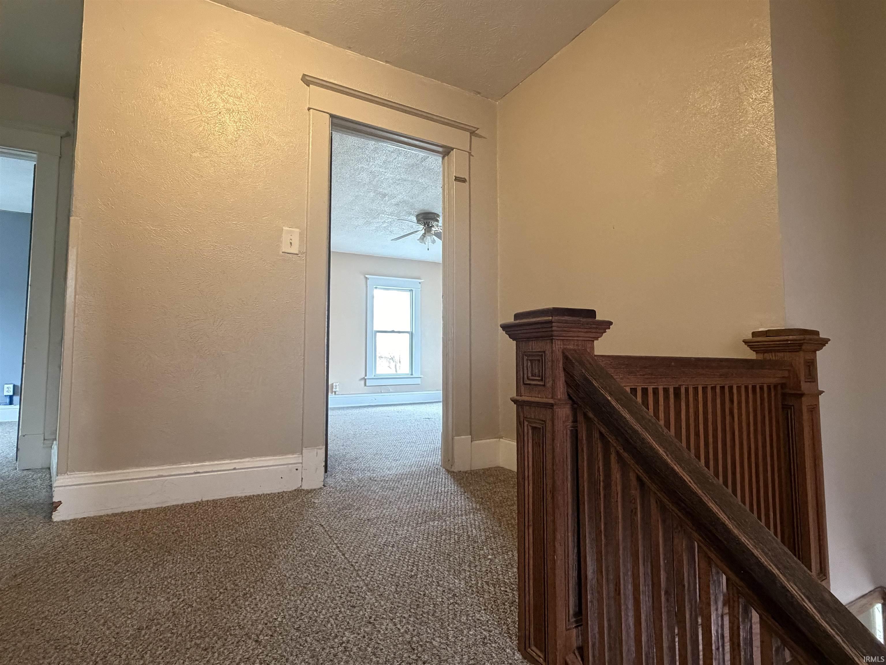 Hallway featuring a textured ceiling, a textured wall, and carpet