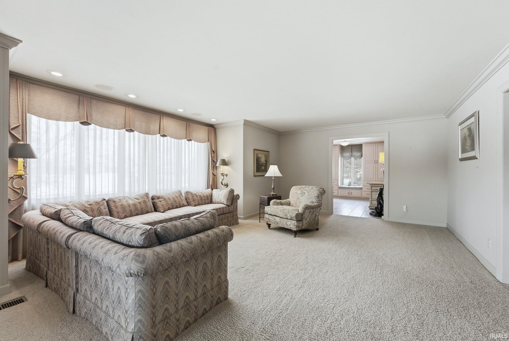 Living room with light carpet, ornamental molding, and a fireplace