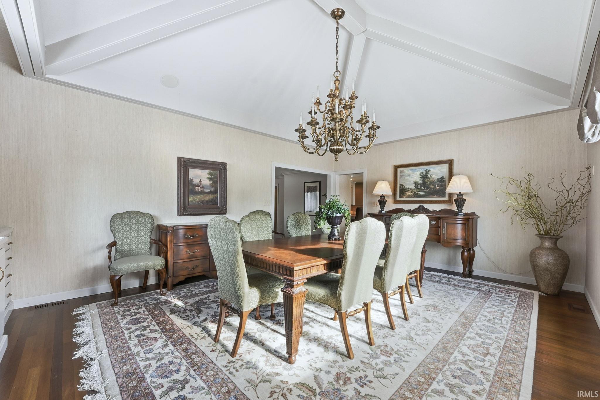 Dining area with a chandelier, dark wood finished floors, and wallpapered walls