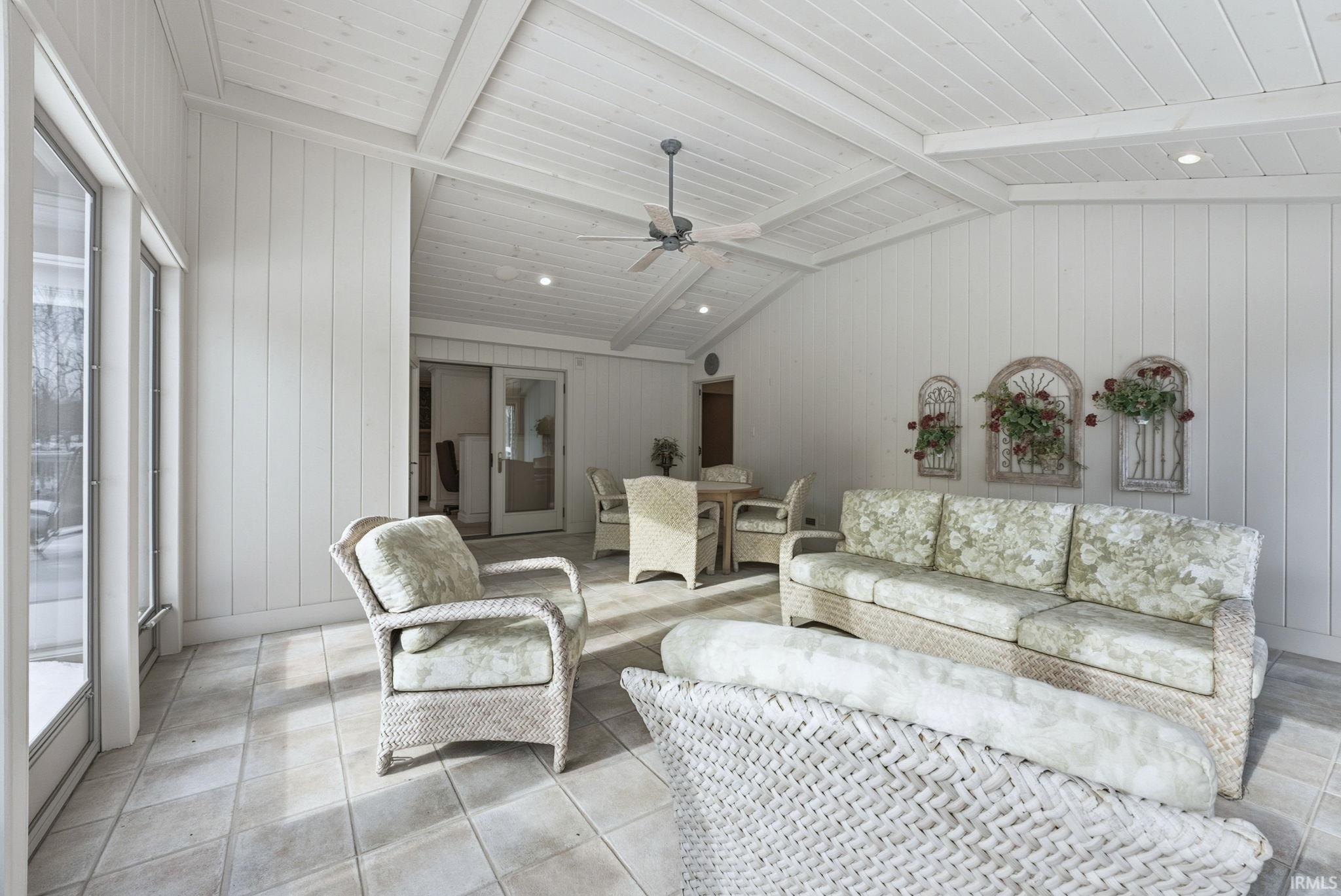 Living area with wooden walls, a ceiling fan, and tile patterned floors