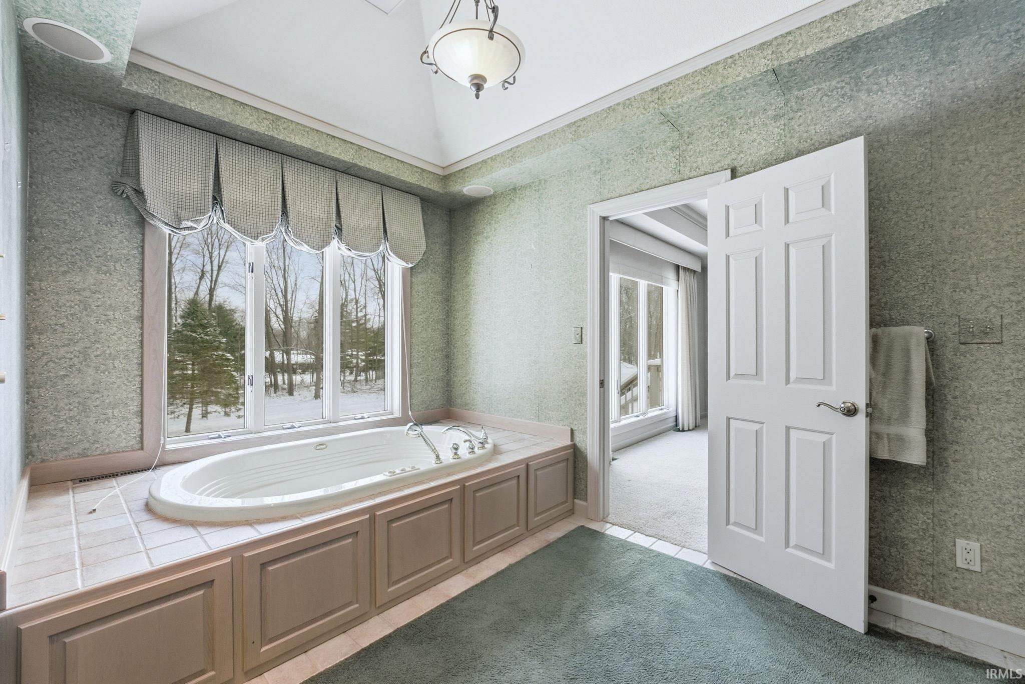 Bathroom featuring wallpapered walls, plenty of natural light, a bath, and tile patterned floors