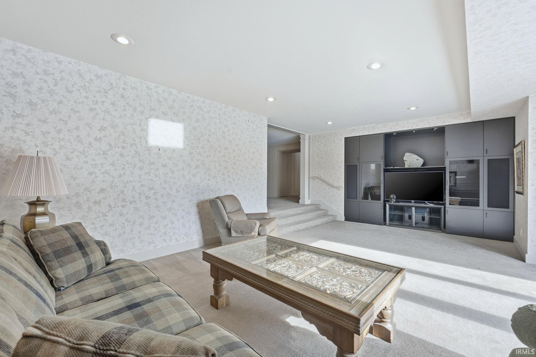 Living area with wallpapered walls, recessed lighting, and carpet flooring