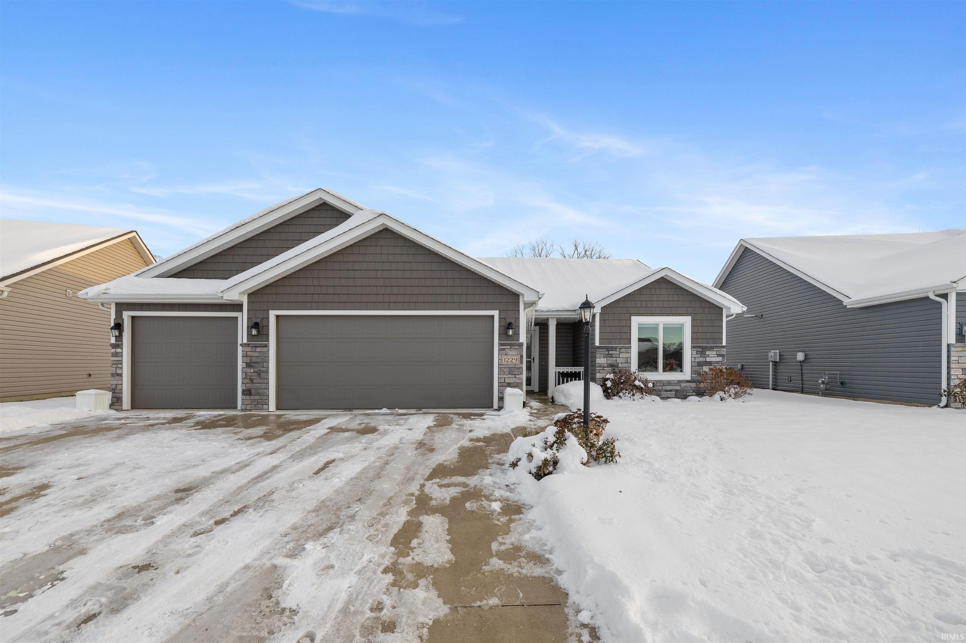 View of front of house with stone siding, a garage, and driveway