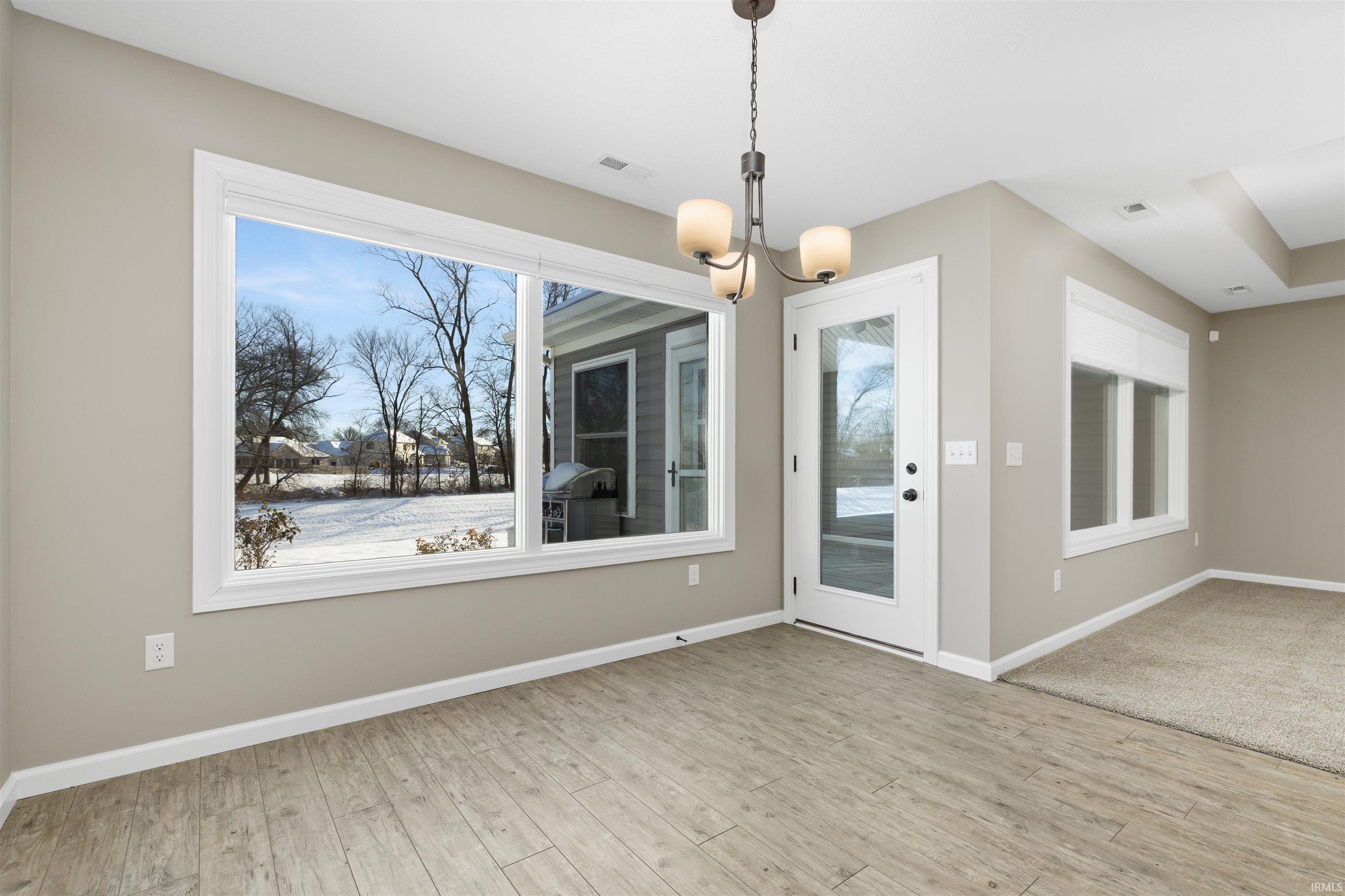 Unfurnished dining area with a chandelier, light wood-type flooring, and plenty of natural light
