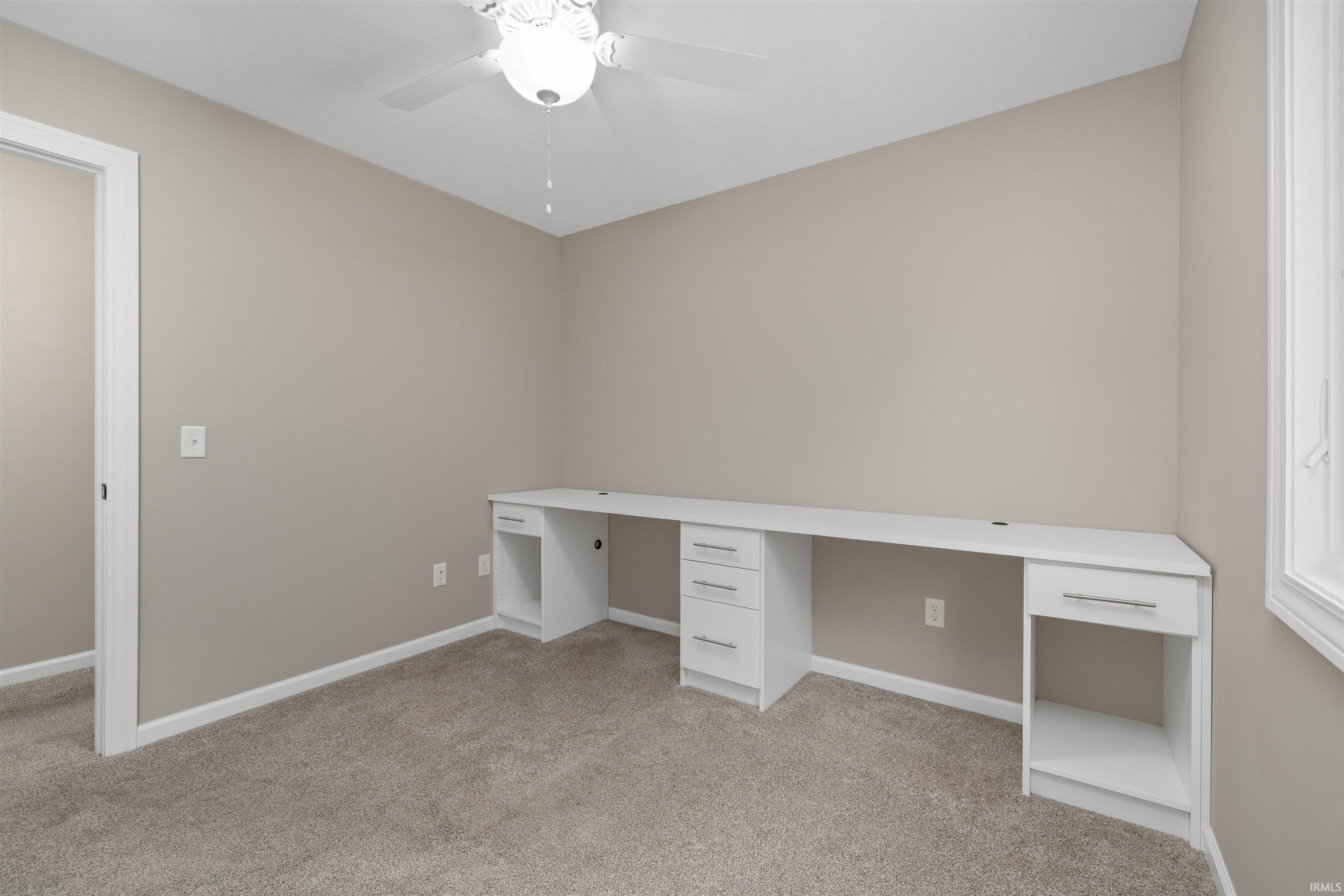 Unfurnished office featuring light colored carpet and a ceiling fan