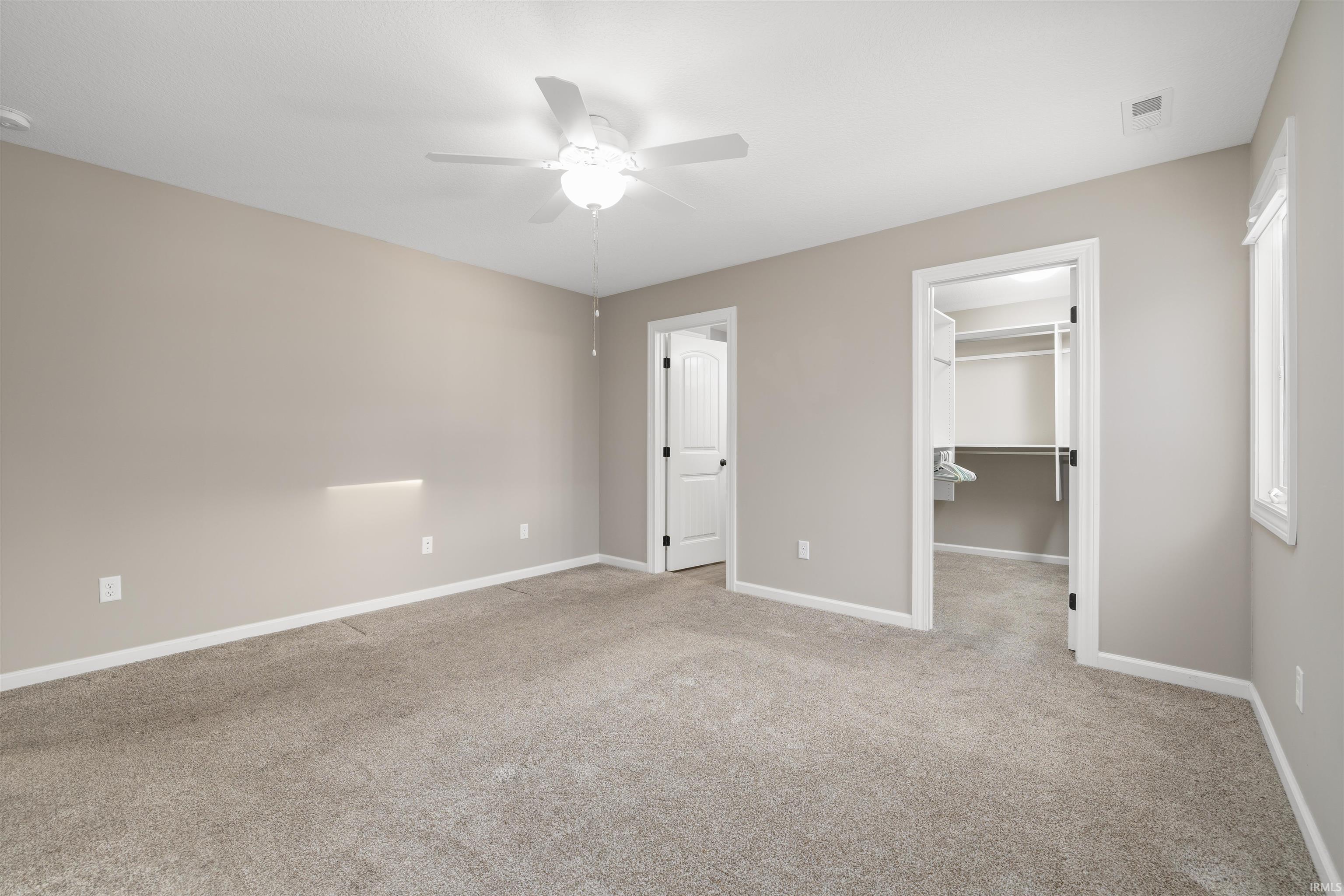 Unfurnished bedroom featuring light carpet, a spacious closet, and ceiling fan