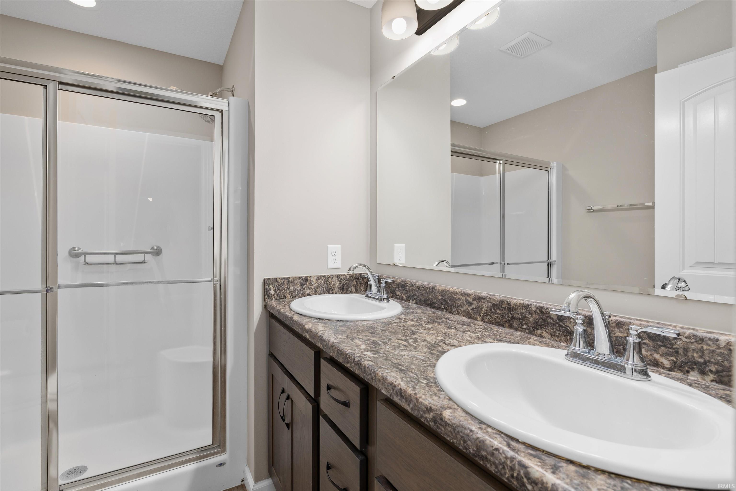 Full bath featuring double vanity, a stall shower, and recessed lighting