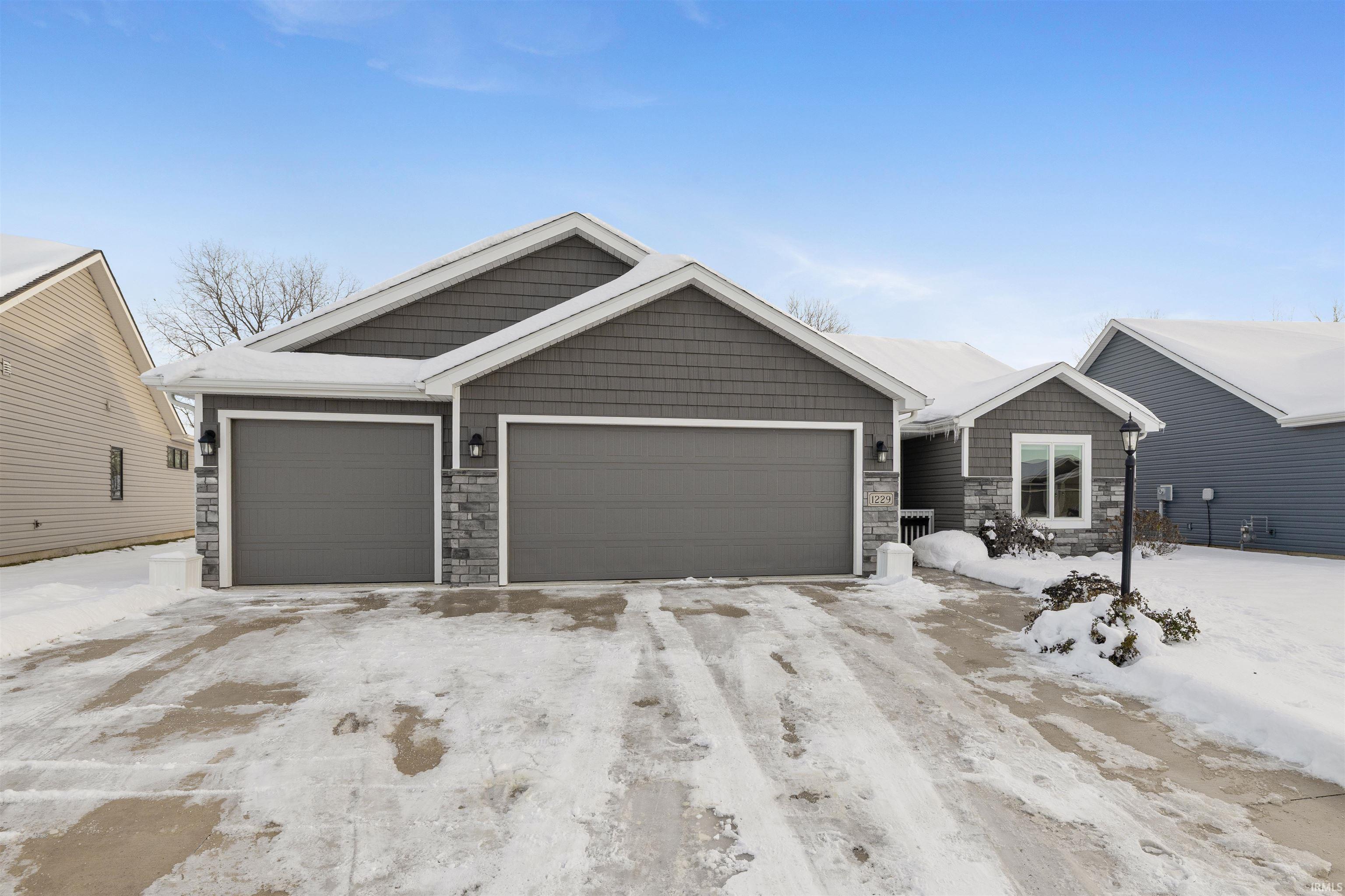 Craftsman inspired home featuring stone siding, driveway, and an attached garage