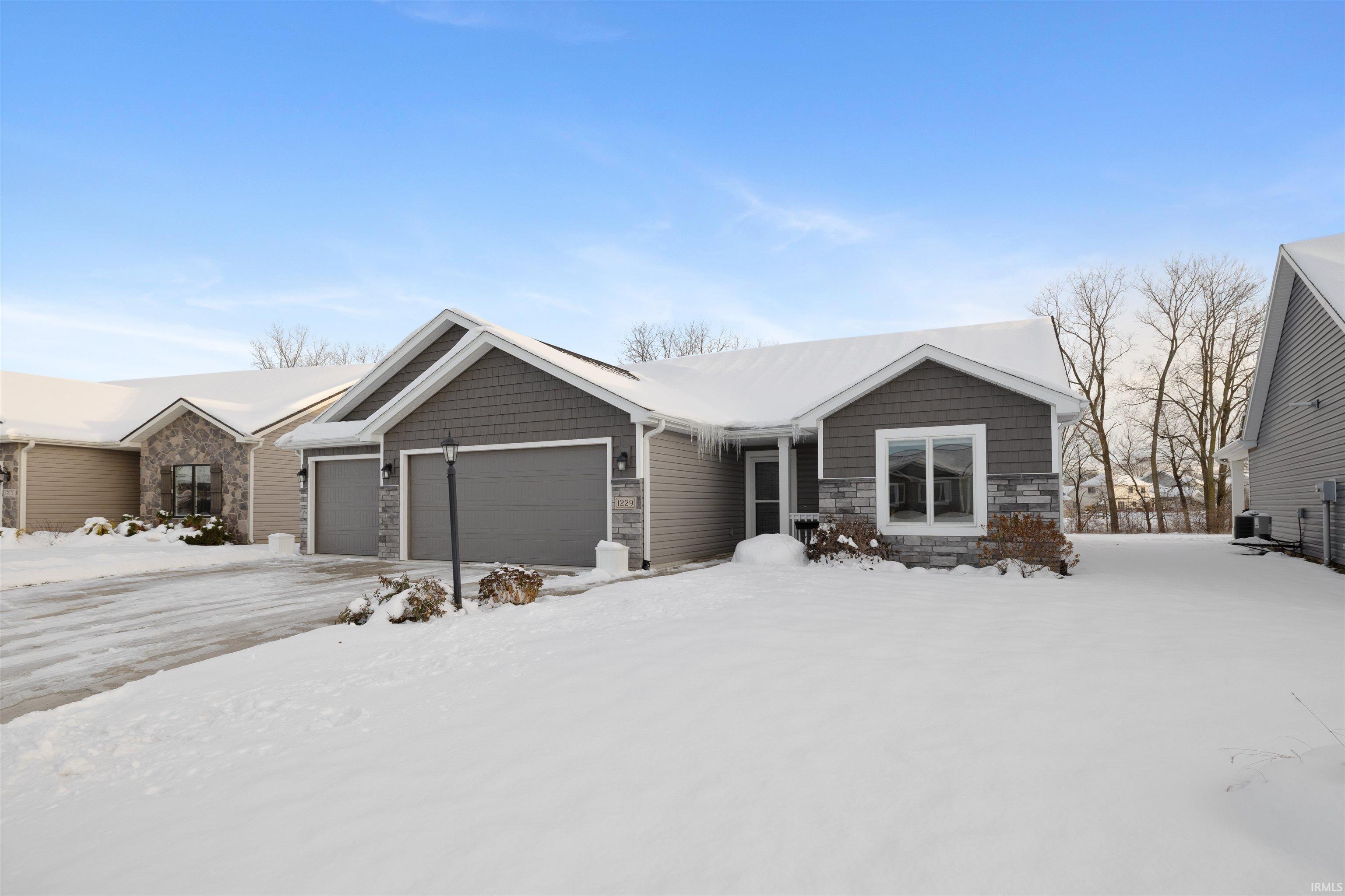 View of front of property featuring stone siding and an attached garage