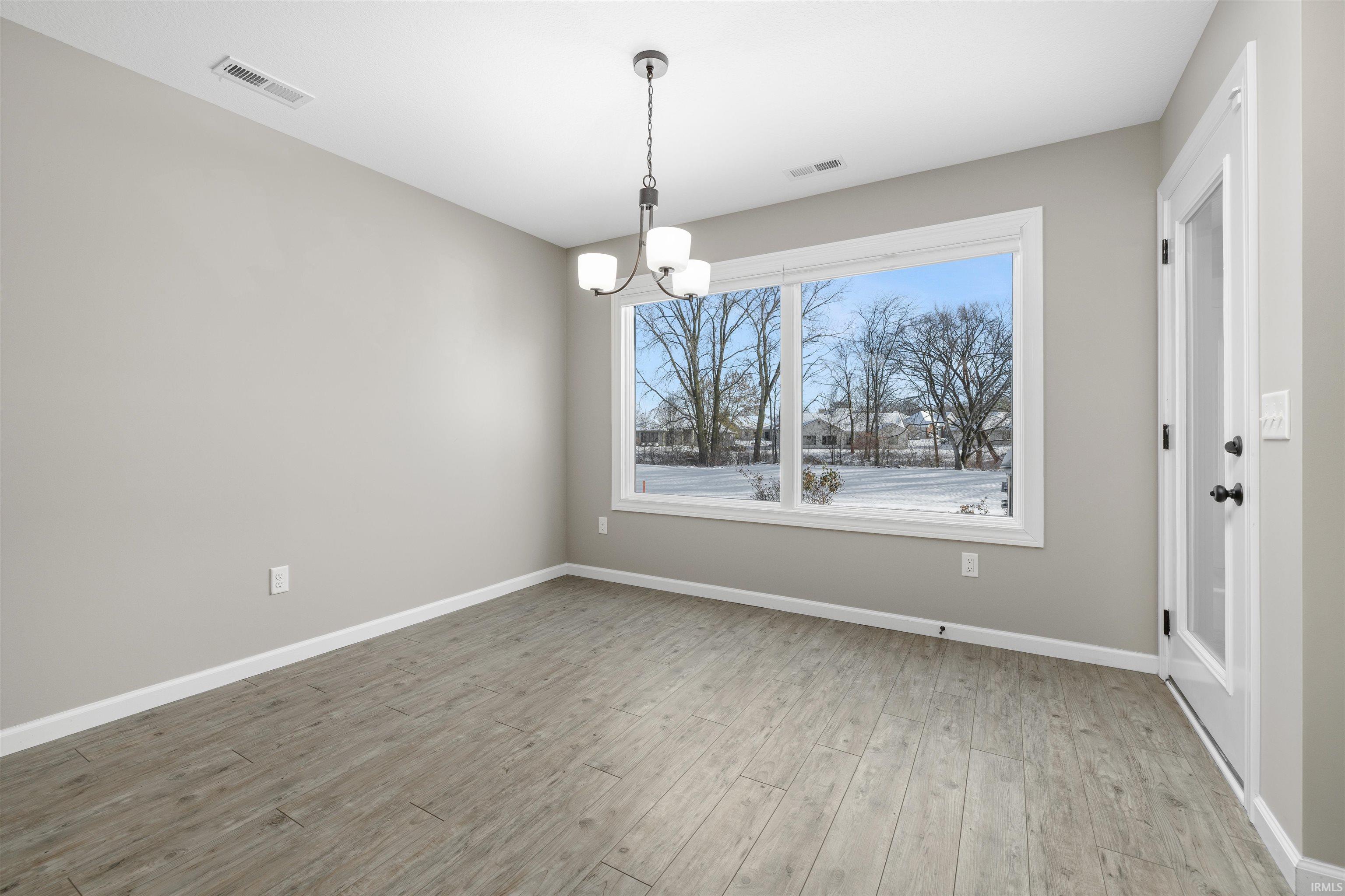 Unfurnished dining area with light wood-style flooring and a chandelier