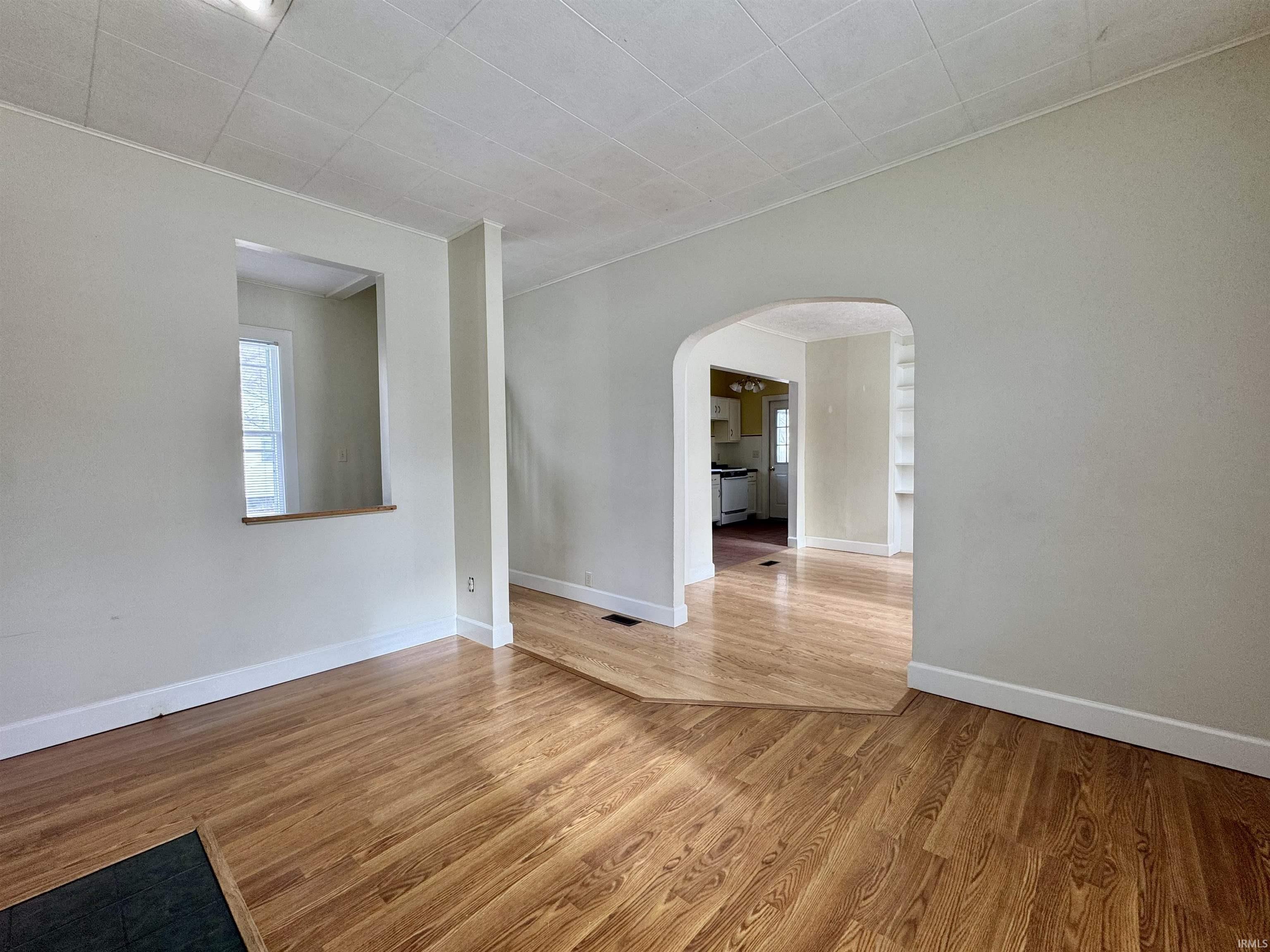Empty room featuring arched walkways and wood finished floors