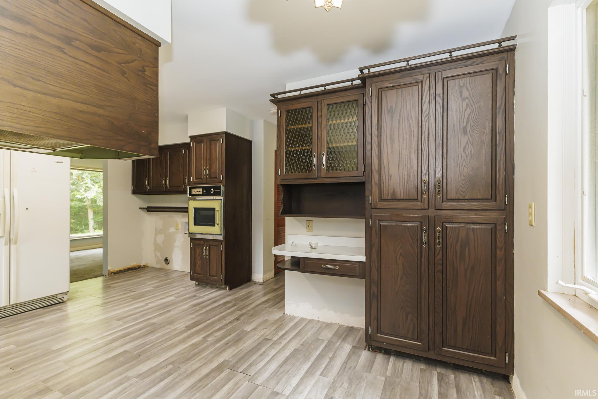 Kitchen space featuring extensive wood-finish cabinetry, built-in oven, and wood-finish flooring