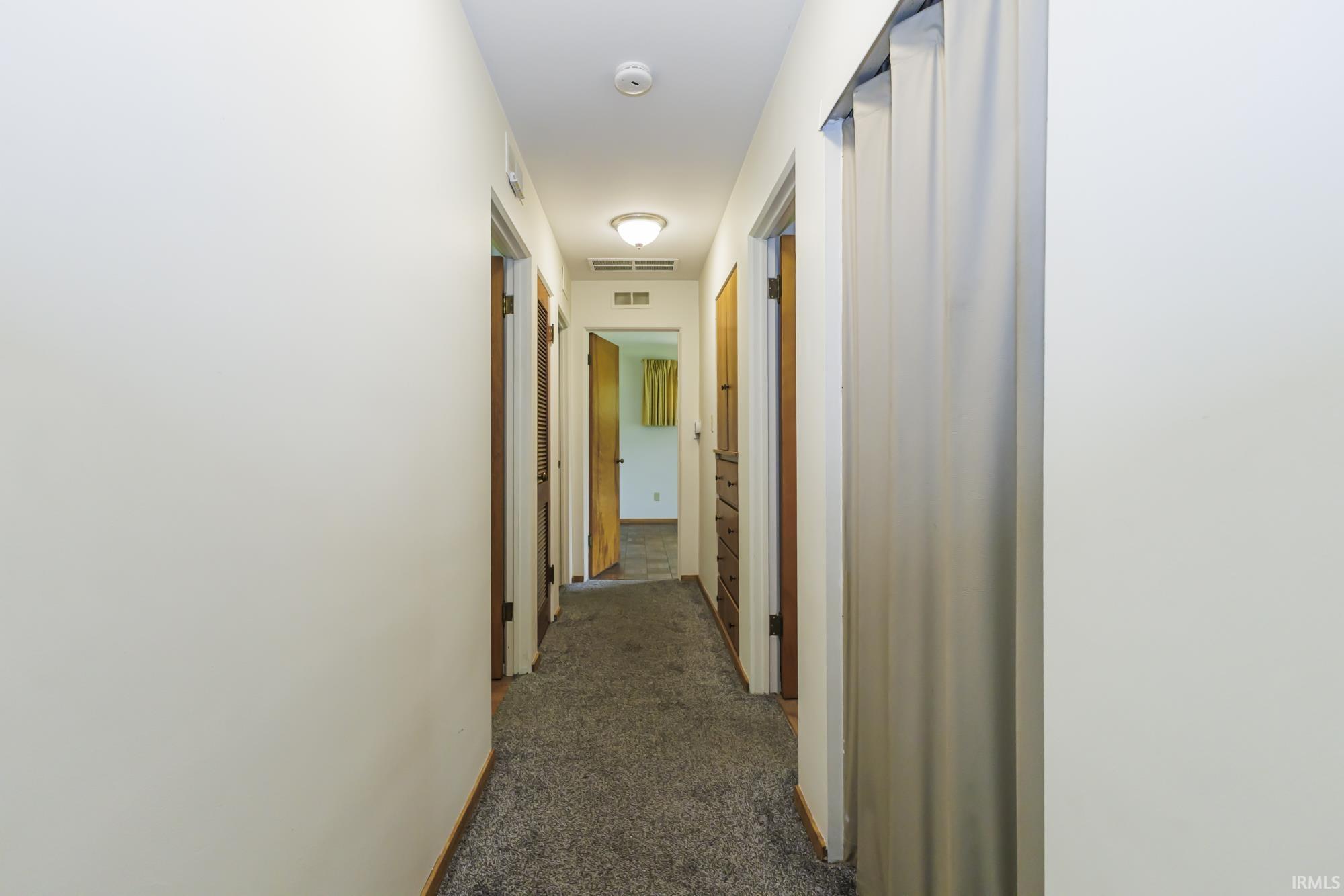 Hallway with neutral carpeting and white walls