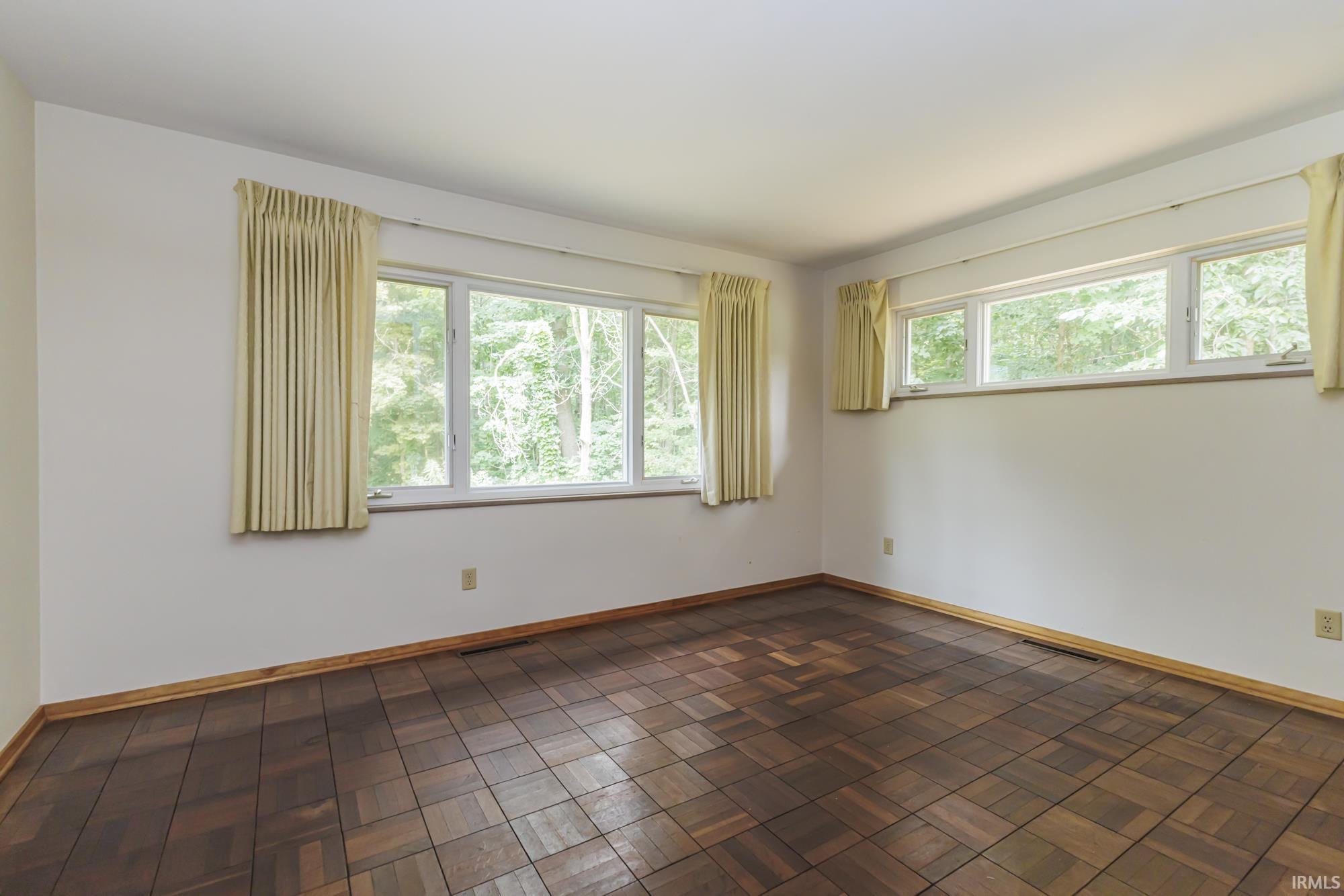 Room featuring parquet flooring and multiple windows