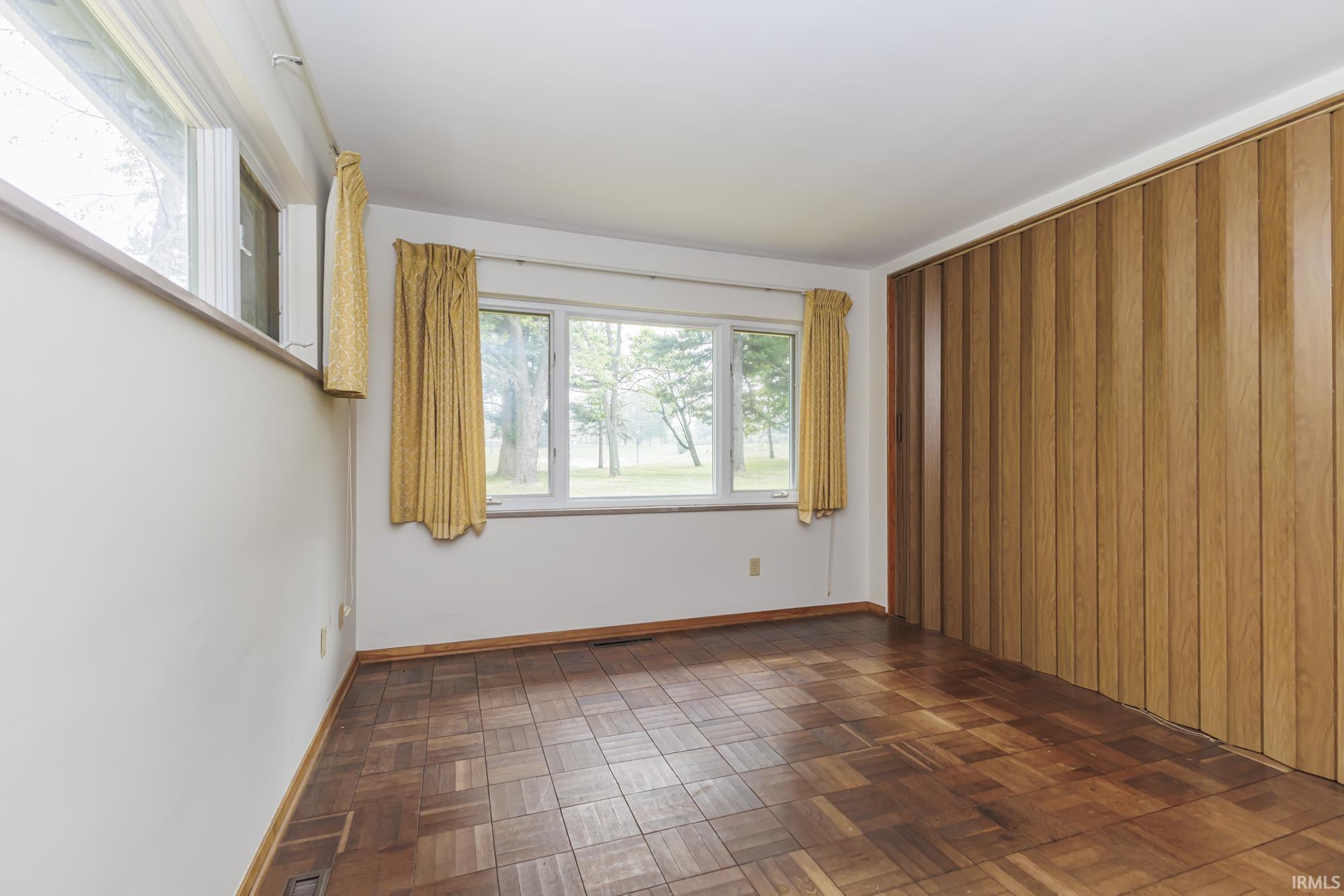 Room featuring parquet wood flooring, white walls, and a wood-paneled accent wall