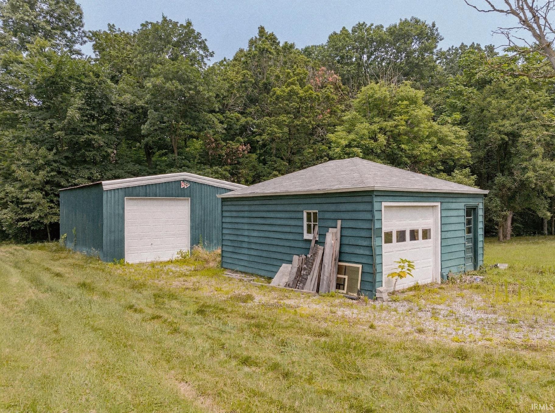 Two detached garages with green siding and white garage doors