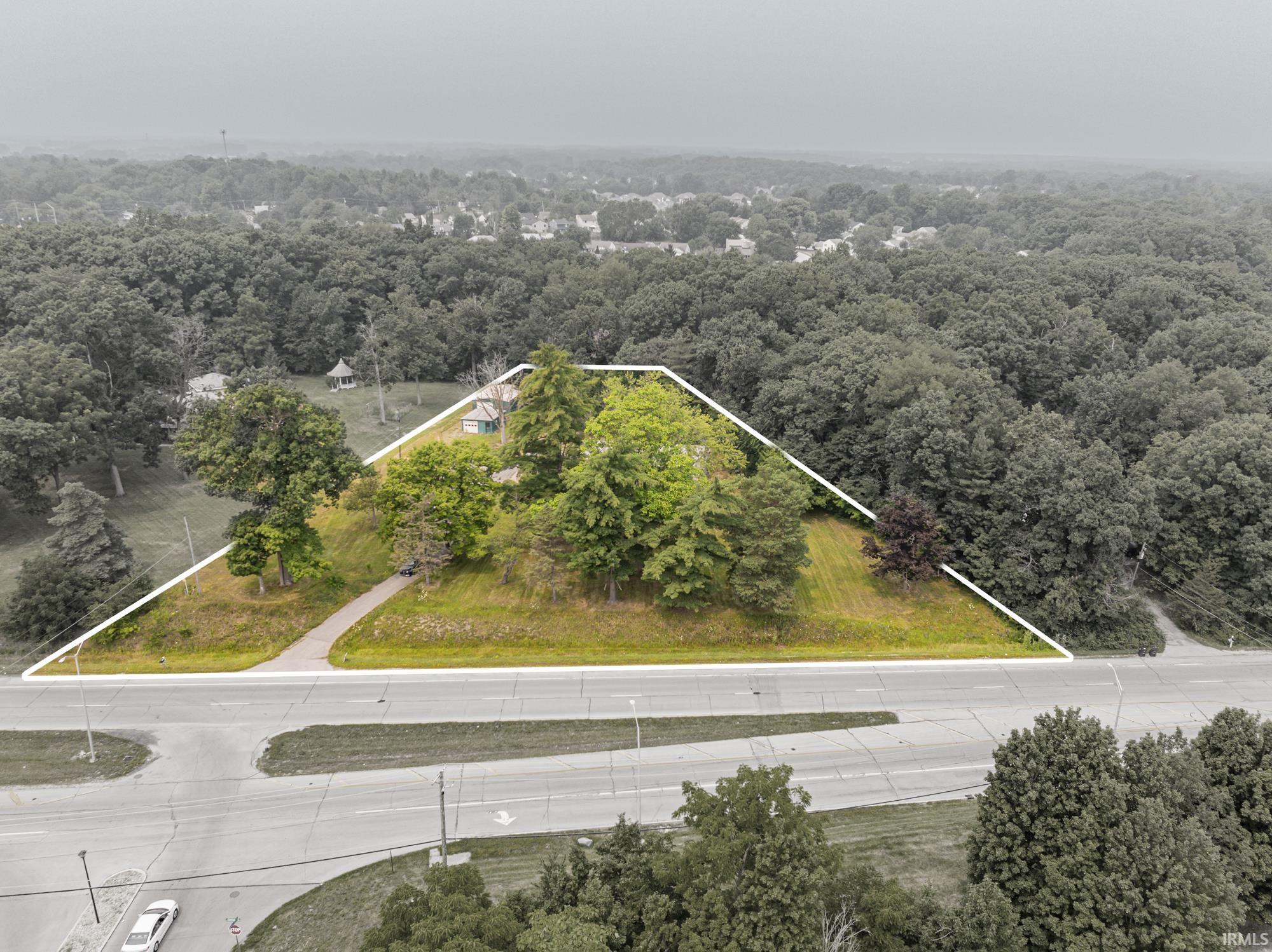 Elevated parcel featuring a sloped grade, established trees, and a paved driveway