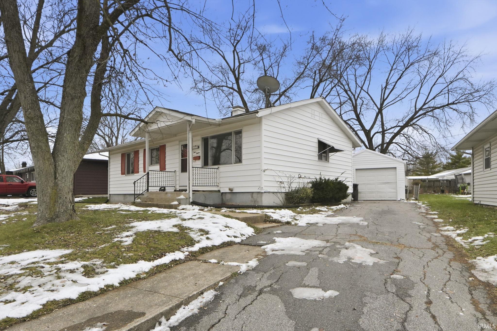 View of front of property featuring a chimney, driveway, and a garage