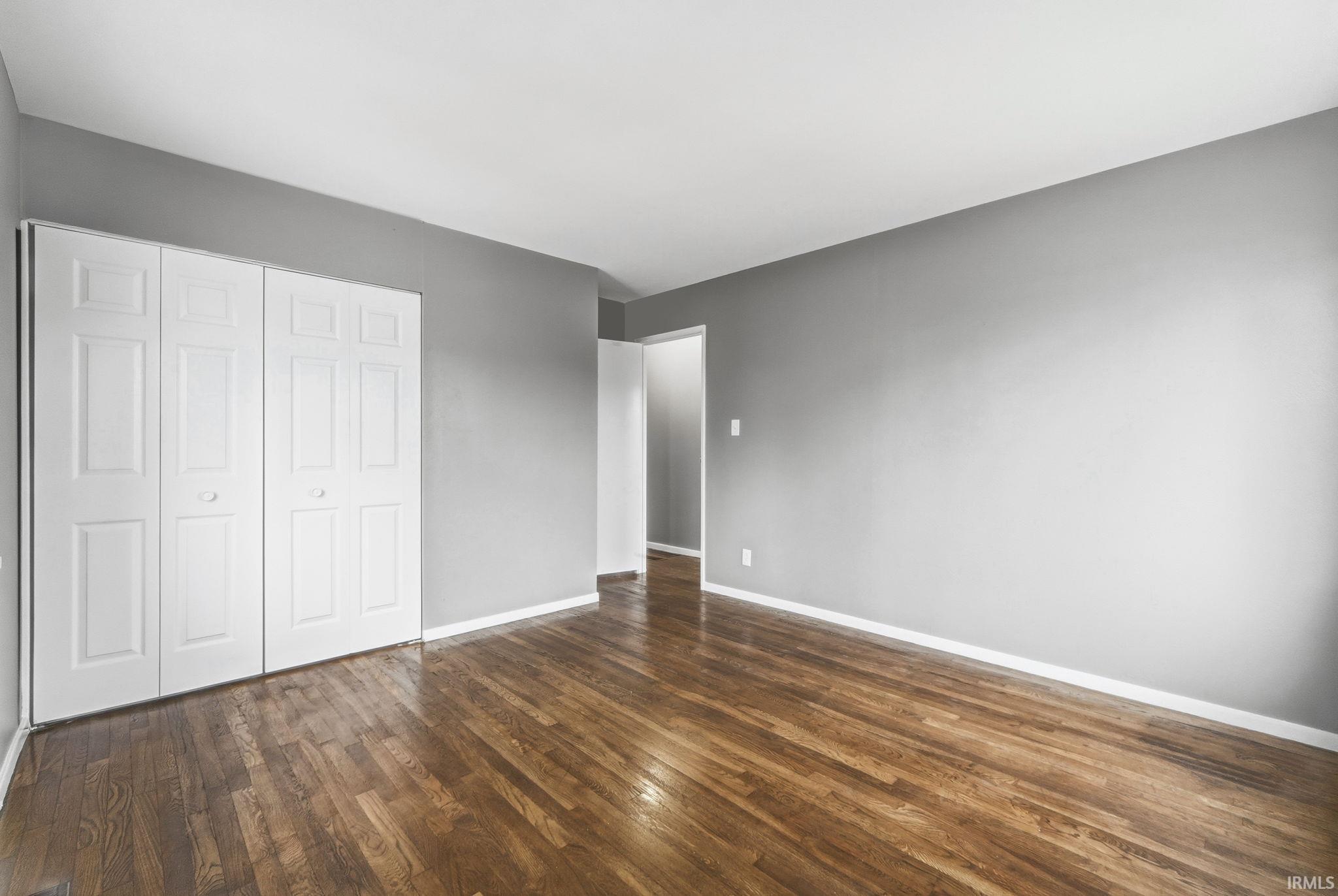 Unfurnished bedroom featuring a closet and dark wood-type flooring