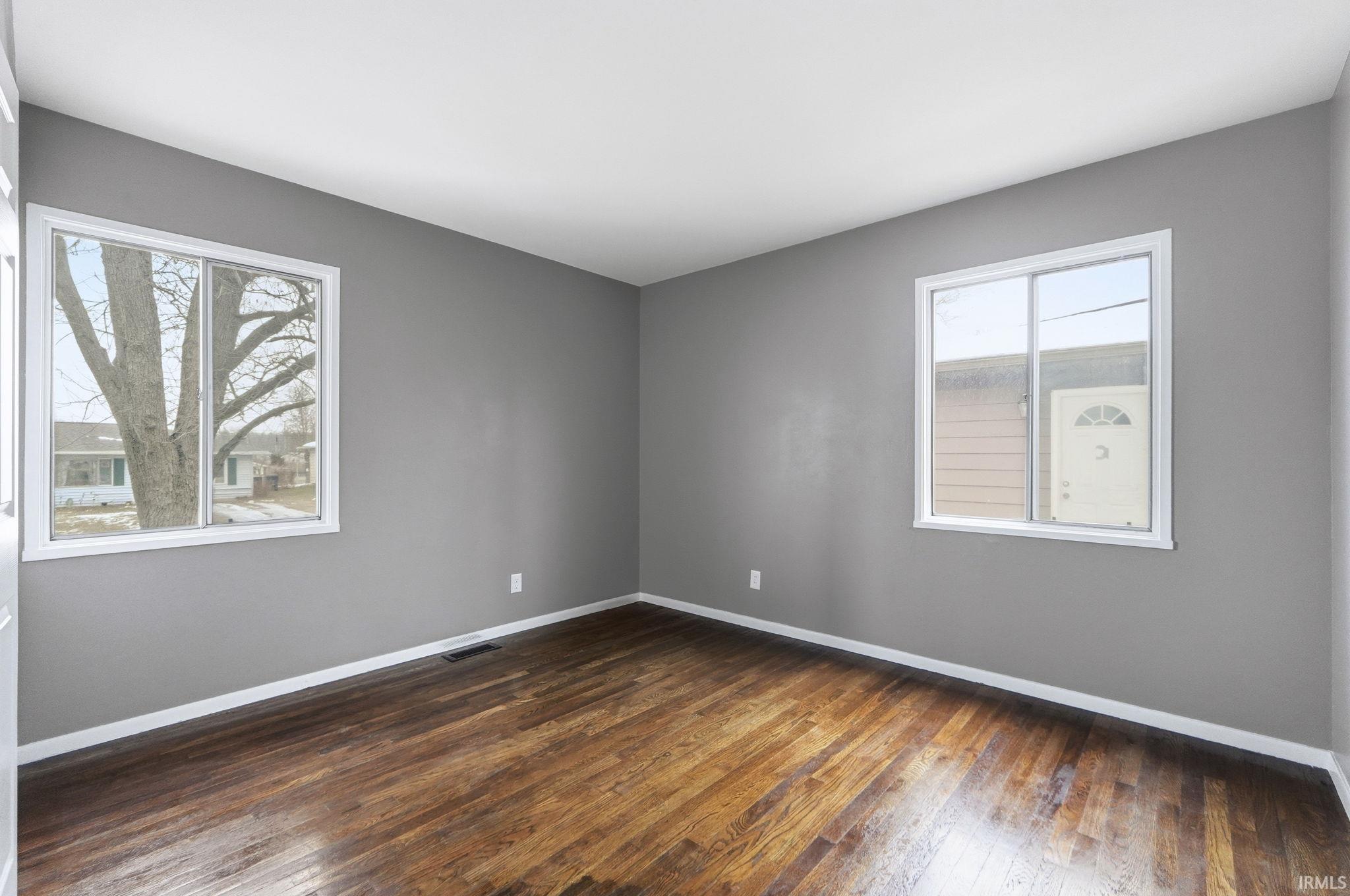 Empty room with dark wood-style floors and baseboards