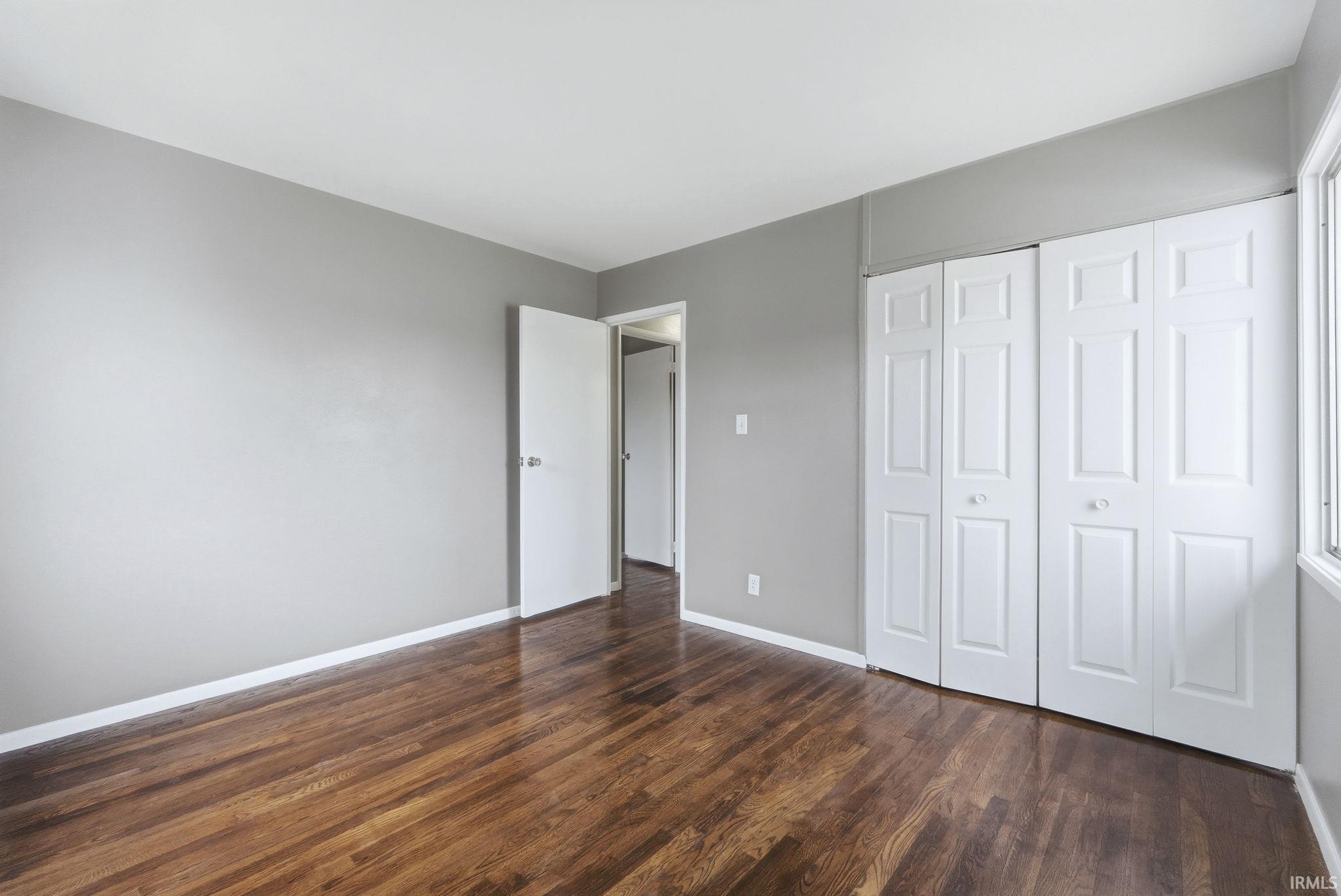 Unfurnished bedroom with a closet and dark wood-style floors