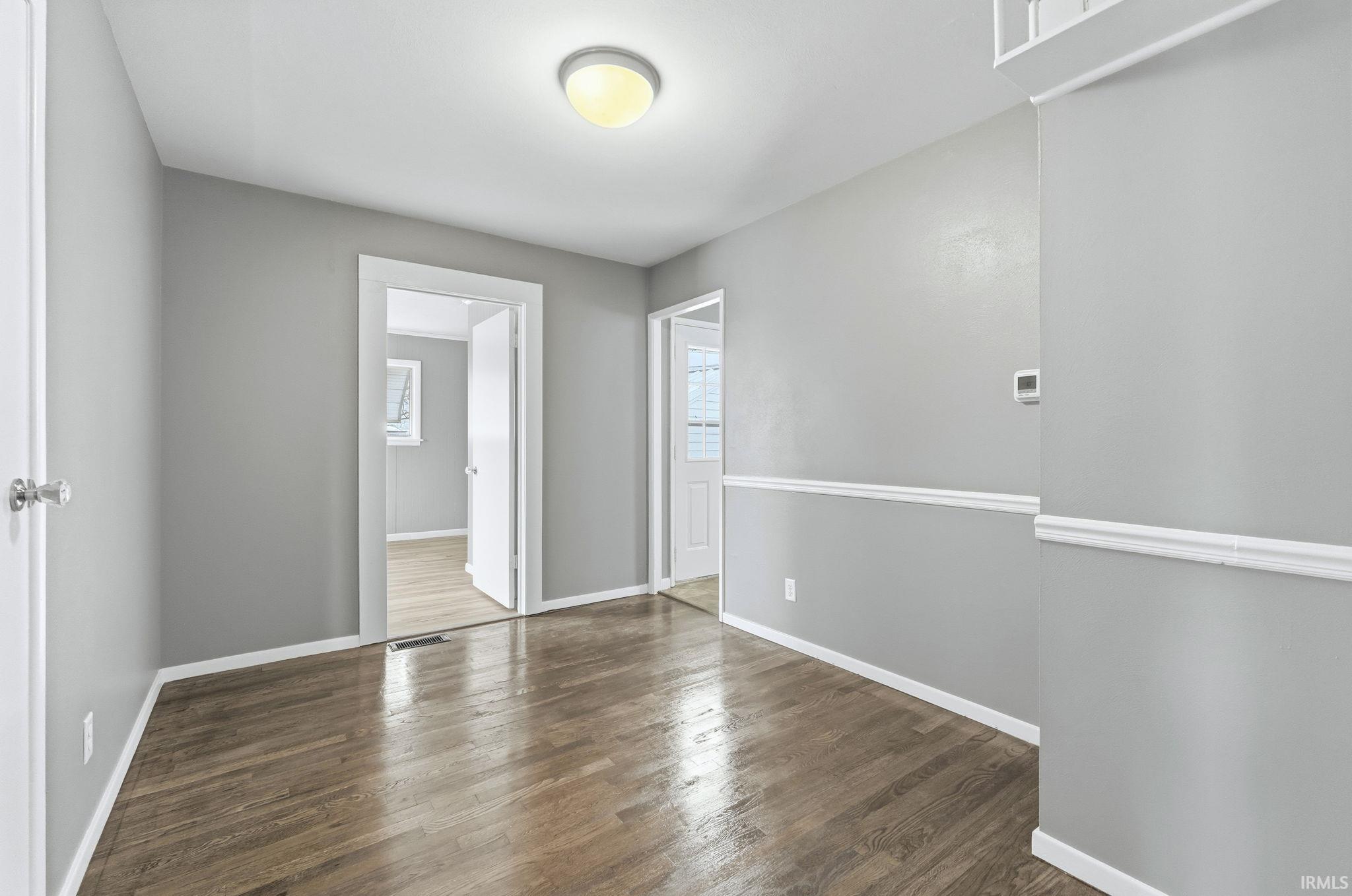 Unfurnished room featuring dark wood finished floors and baseboards
