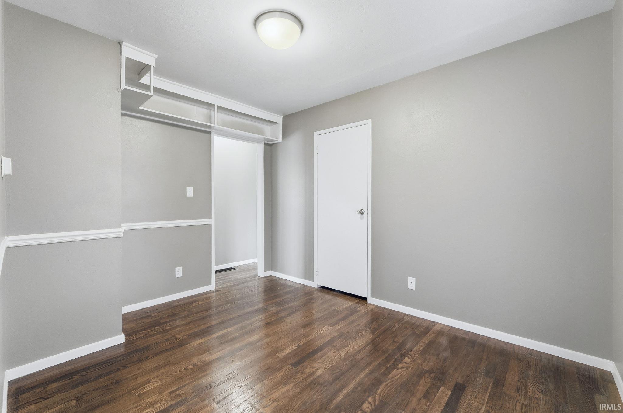 Unfurnished bedroom featuring dark wood finished floors and baseboards