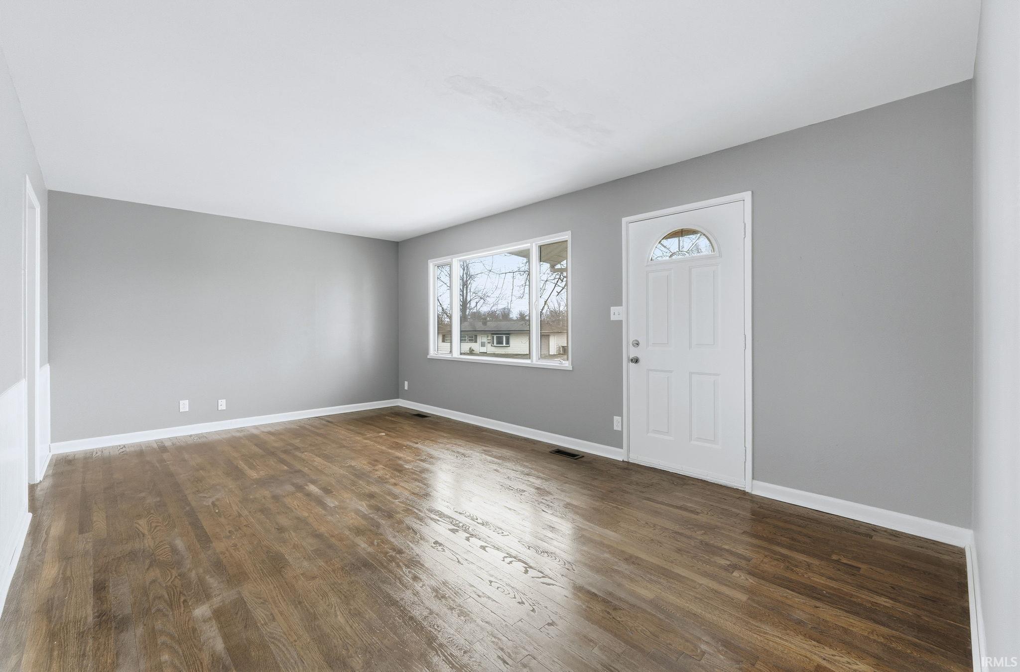 Foyer featuring dark wood-style flooring and baseboards