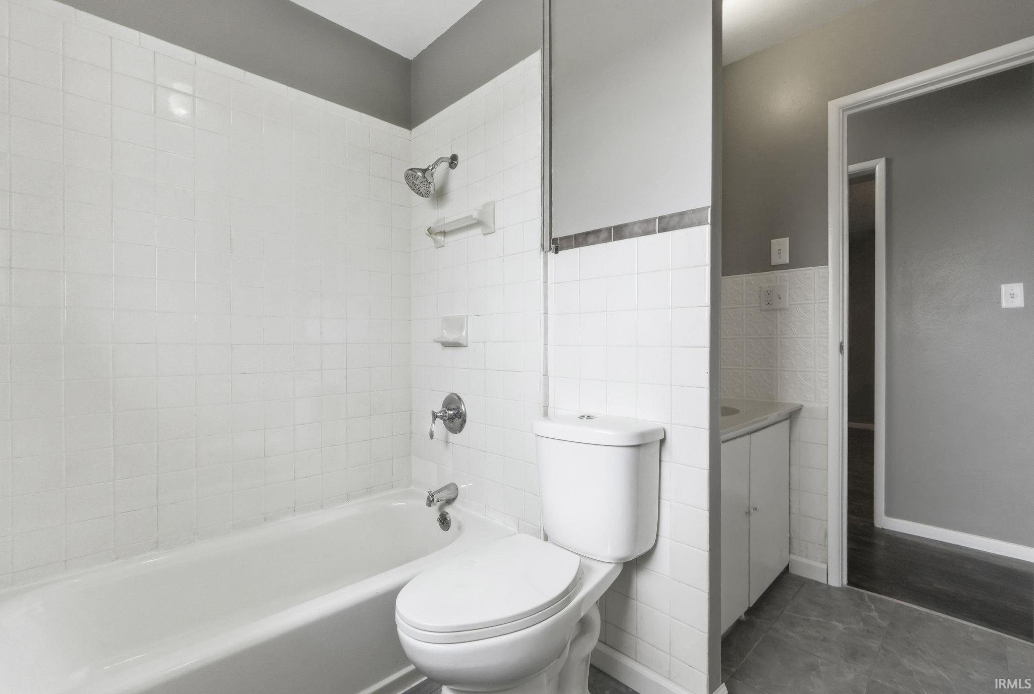 Bathroom with vanity,  shower combination, and tile walls