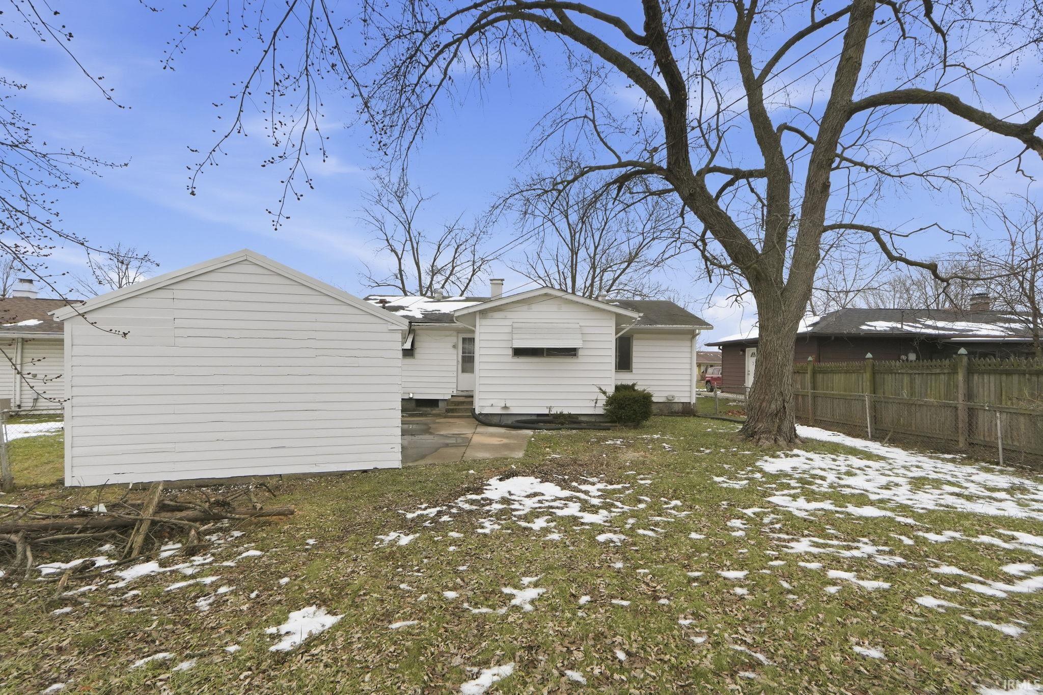 Snow covered rear of property with a patio and entry steps