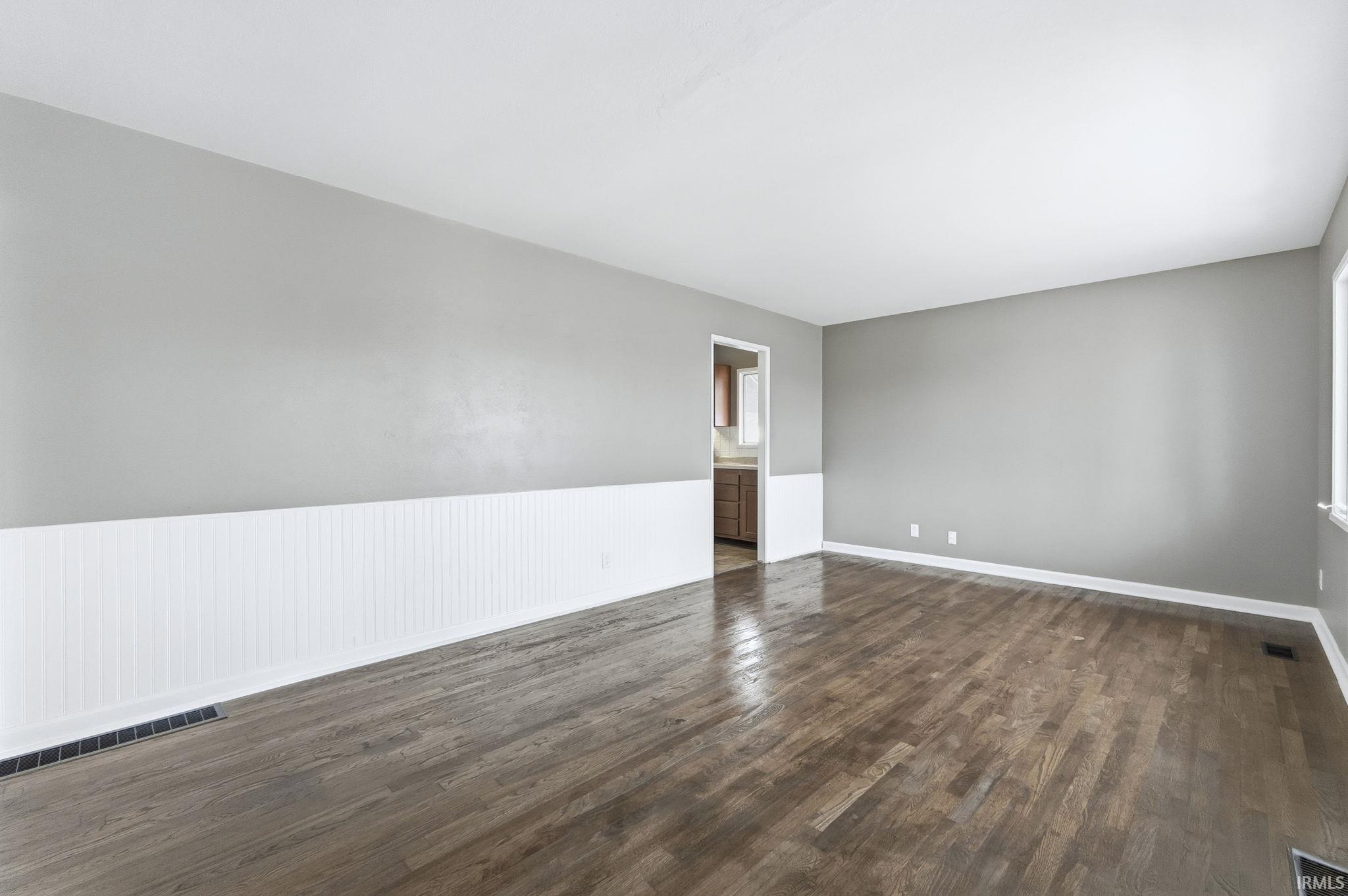 Unfurnished room featuring dark wood finished floors and baseboards