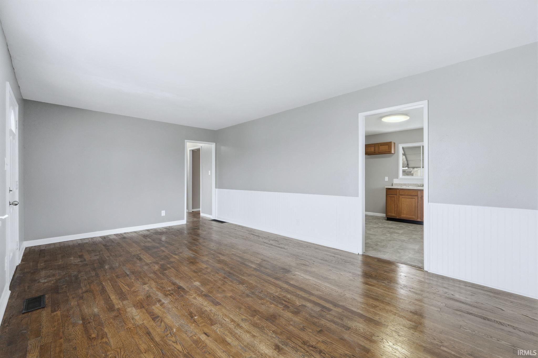 Empty room featuring dark wood-type flooring and wainscoting