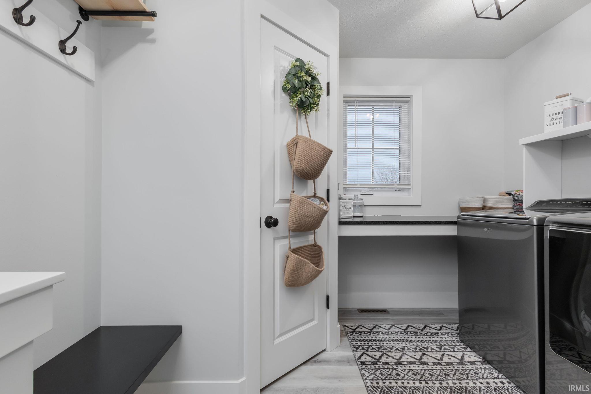 Washroom with washing machine and dryer and light wood-style flooring