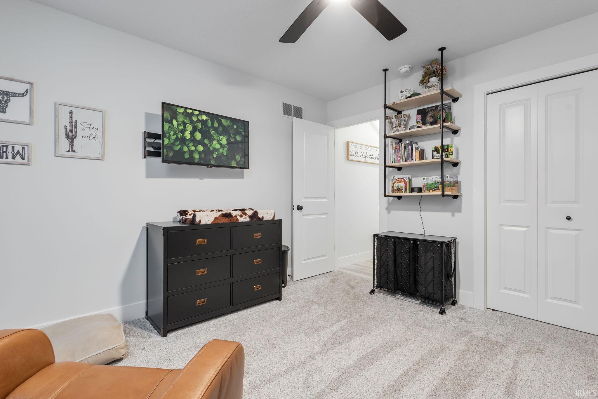 Sitting room with light carpet and a ceiling fan
