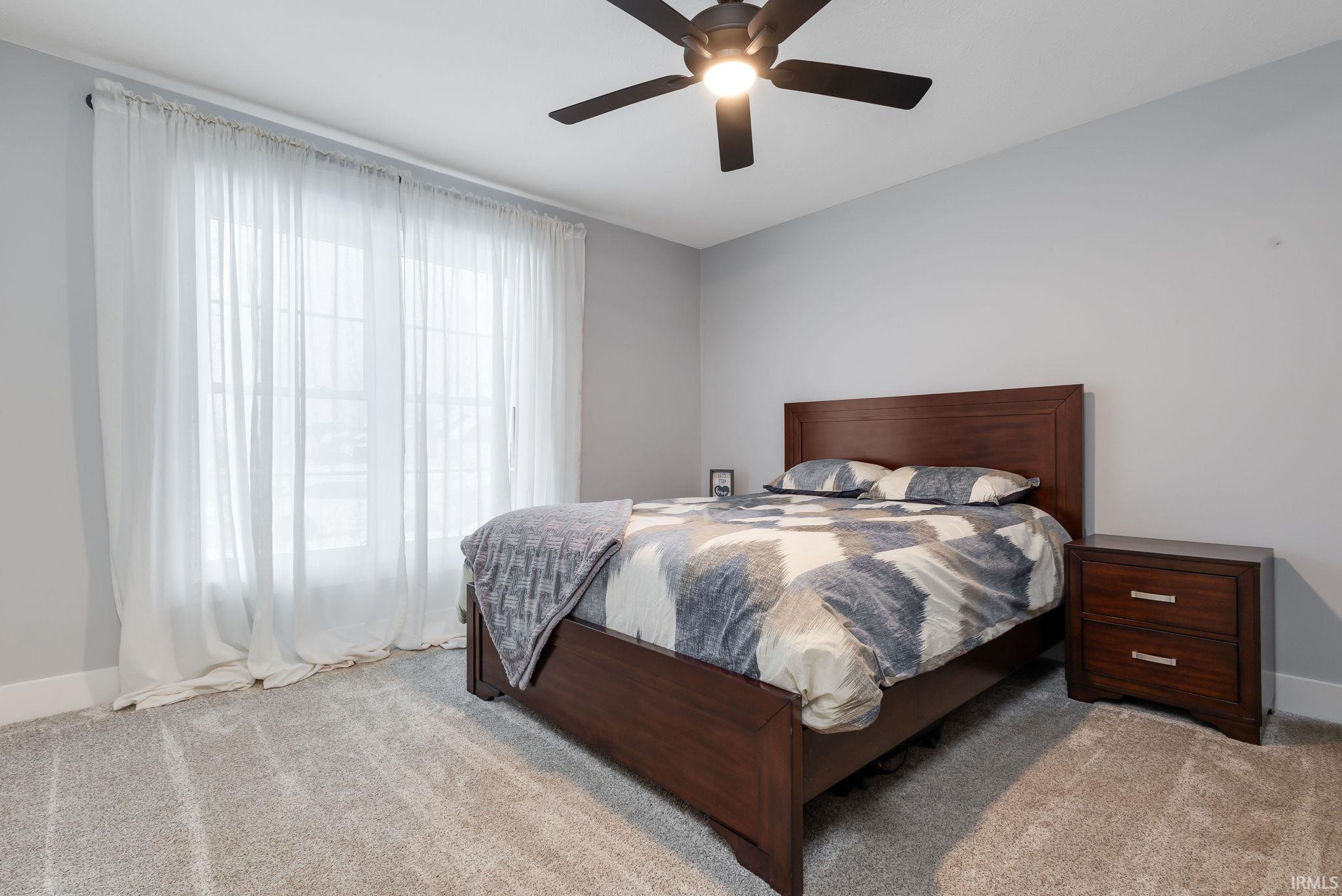 Carpeted bedroom featuring baseboards and a ceiling fan