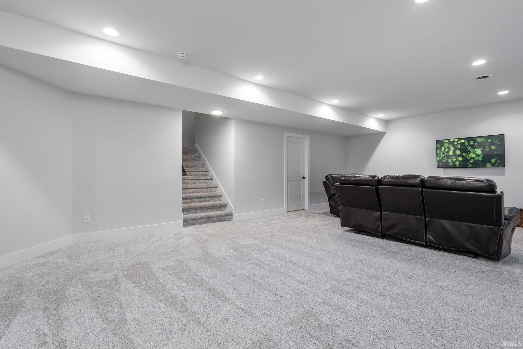 Living room with stairs, light carpet, and recessed lighting