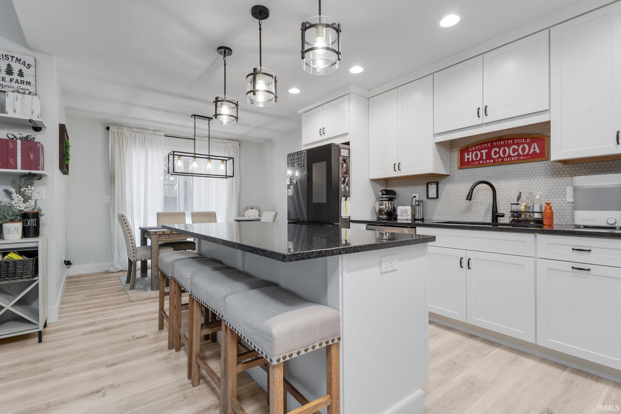 Kitchen with a kitchen bar, backsplash, white cabinetry, a kitchen island, and freestanding refrigerator