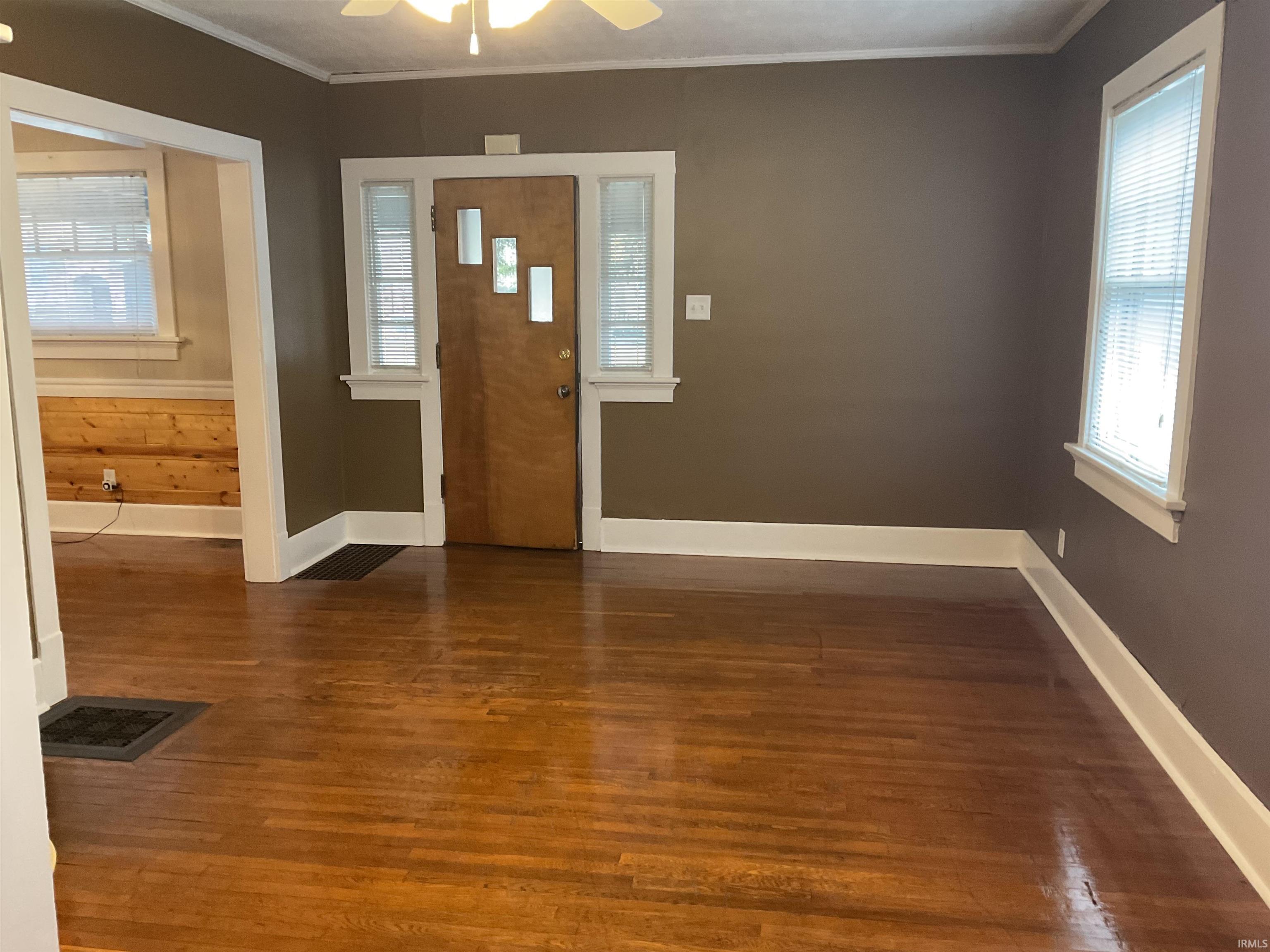 Living room with recently refinished hardwood floors, plenty of natural light, and ceiling fan