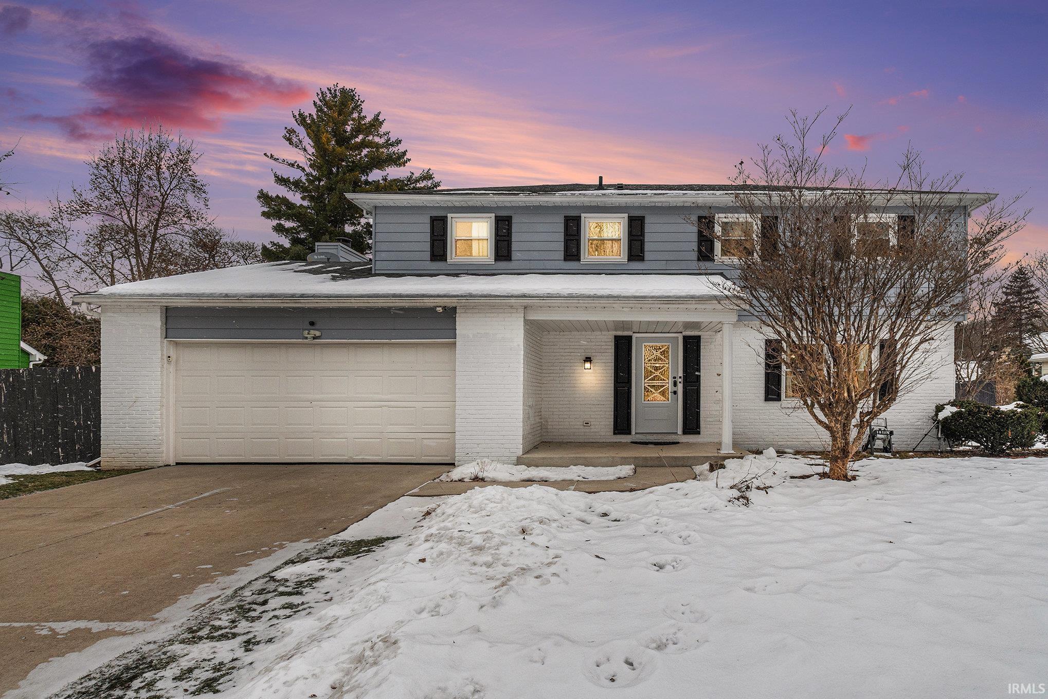 Traditional-style home featuring brick siding, a porch, concrete driveway, and a garage