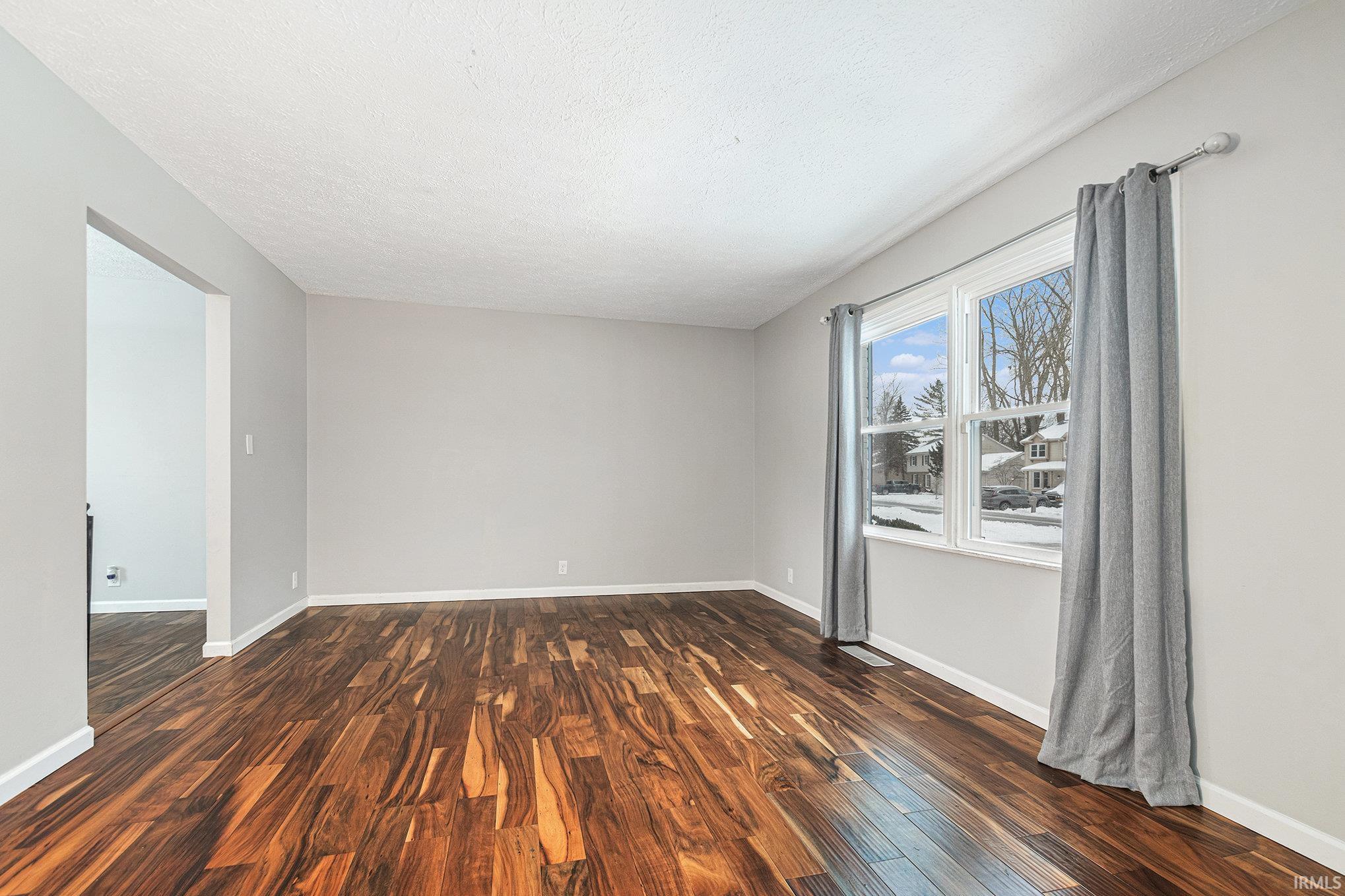 Unfurnished room featuring dark wood-style finished floors and a textured ceiling