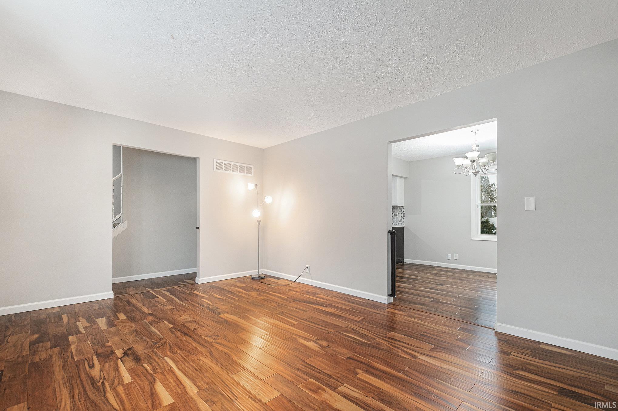 Unfurnished room with dark wood finished floors, a chandelier, and a textured ceiling