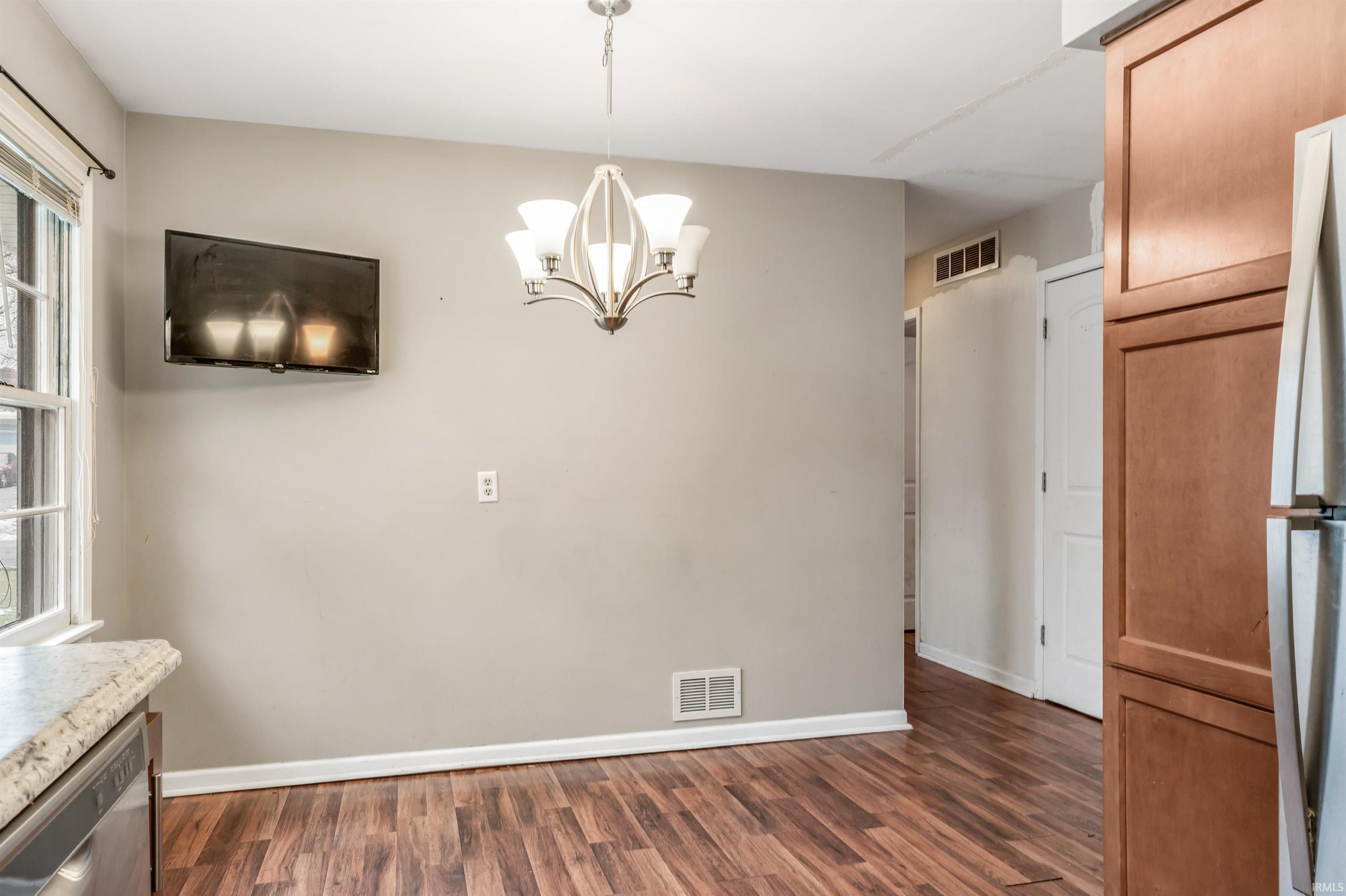 Unfurnished dining area with a chandelier and dark wood-type flooring