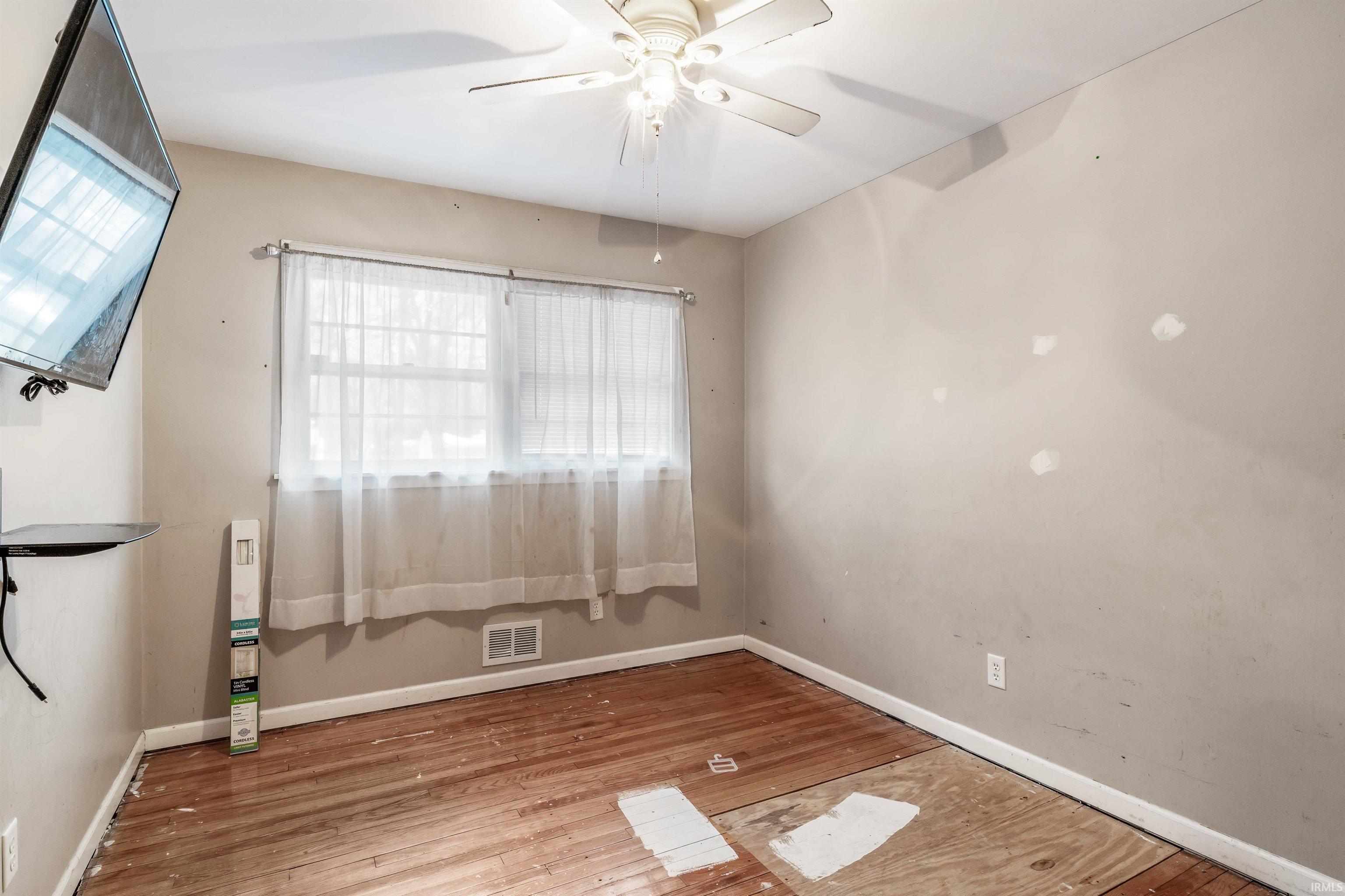 Empty room with plenty of natural light, ceiling fan, and light wood-style flooring