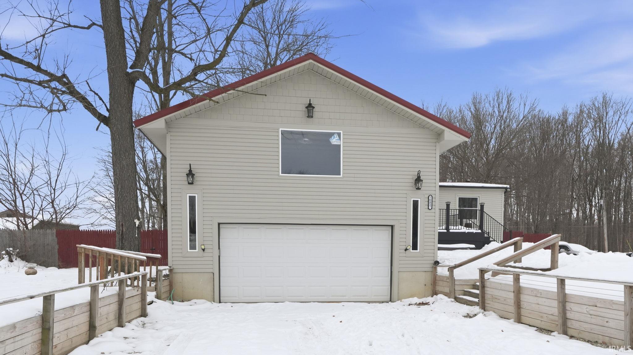 View of snowy exterior featuring an attached garage