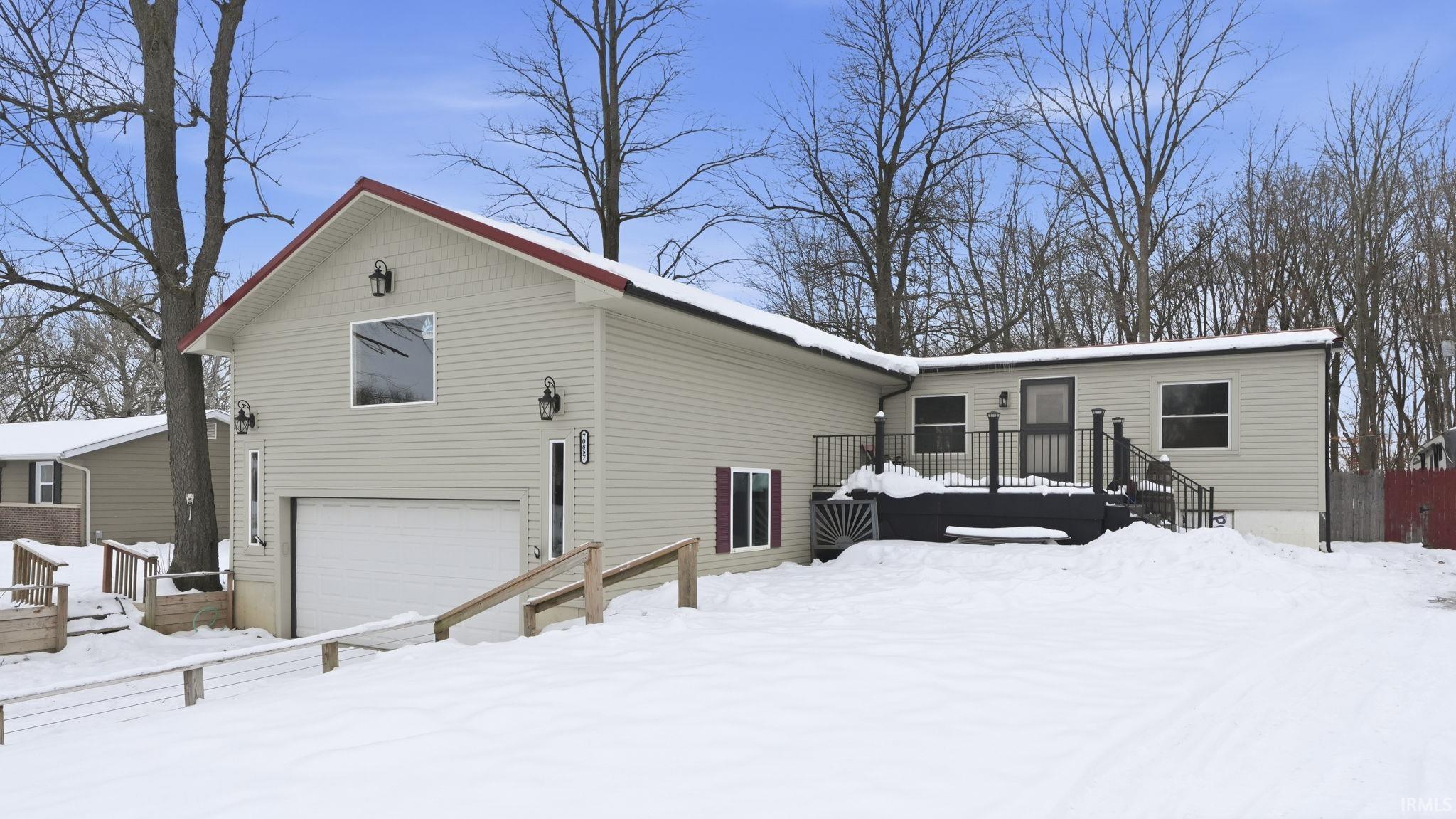 Snow covered property with a deck and an attached garage