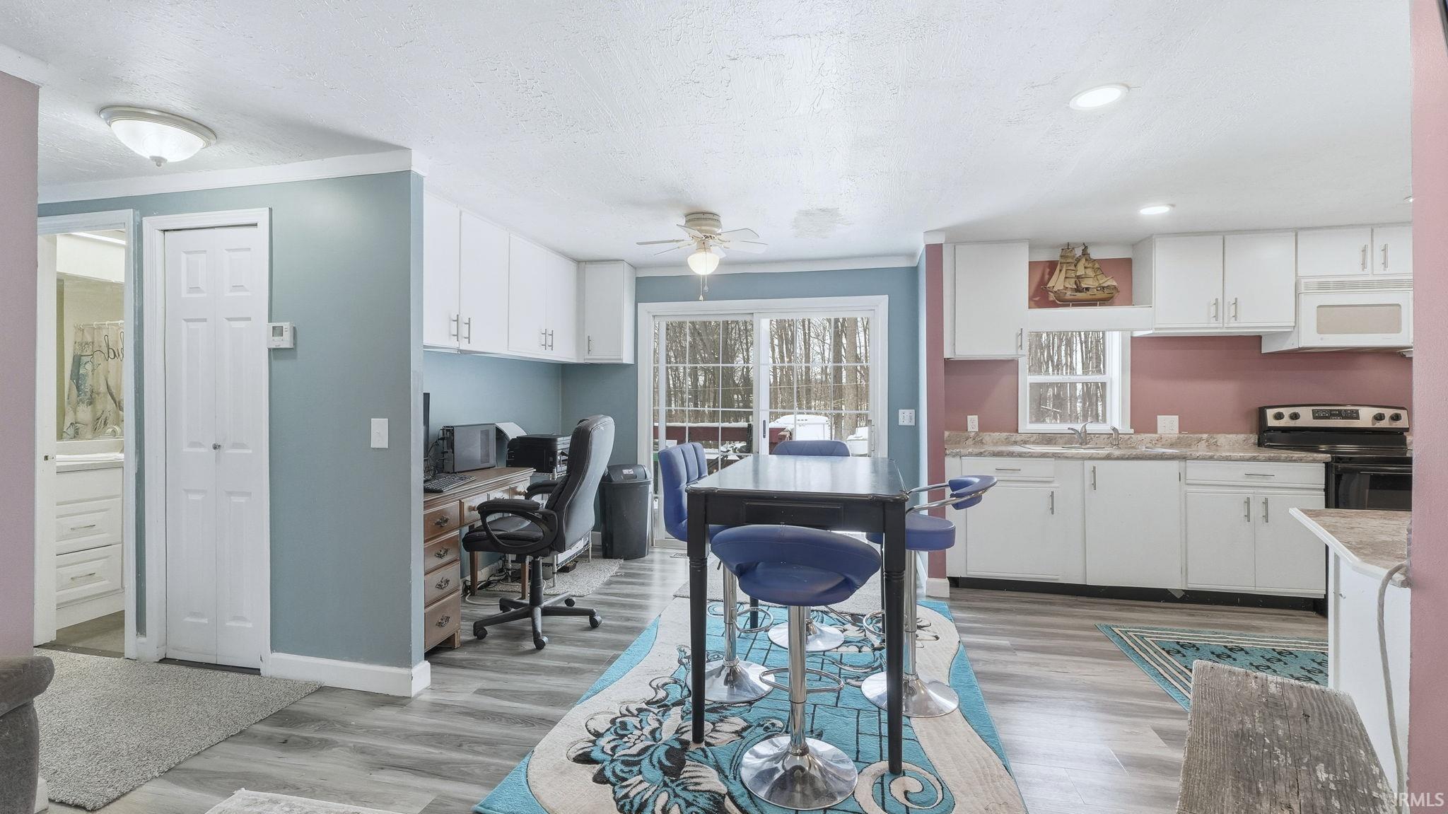 Kitchen with white cabinetry, light countertops, black electric range oven, a textured ceiling, and light wood-style floors