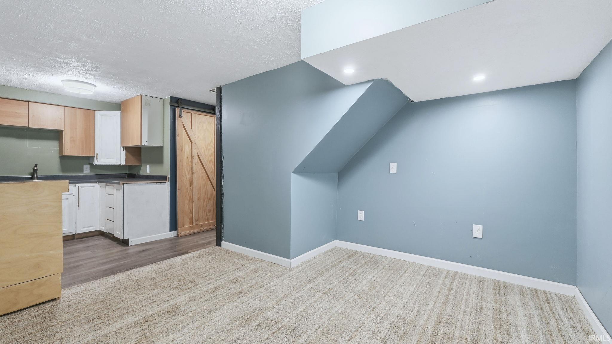 Additional living space with a textured ceiling and baseboards