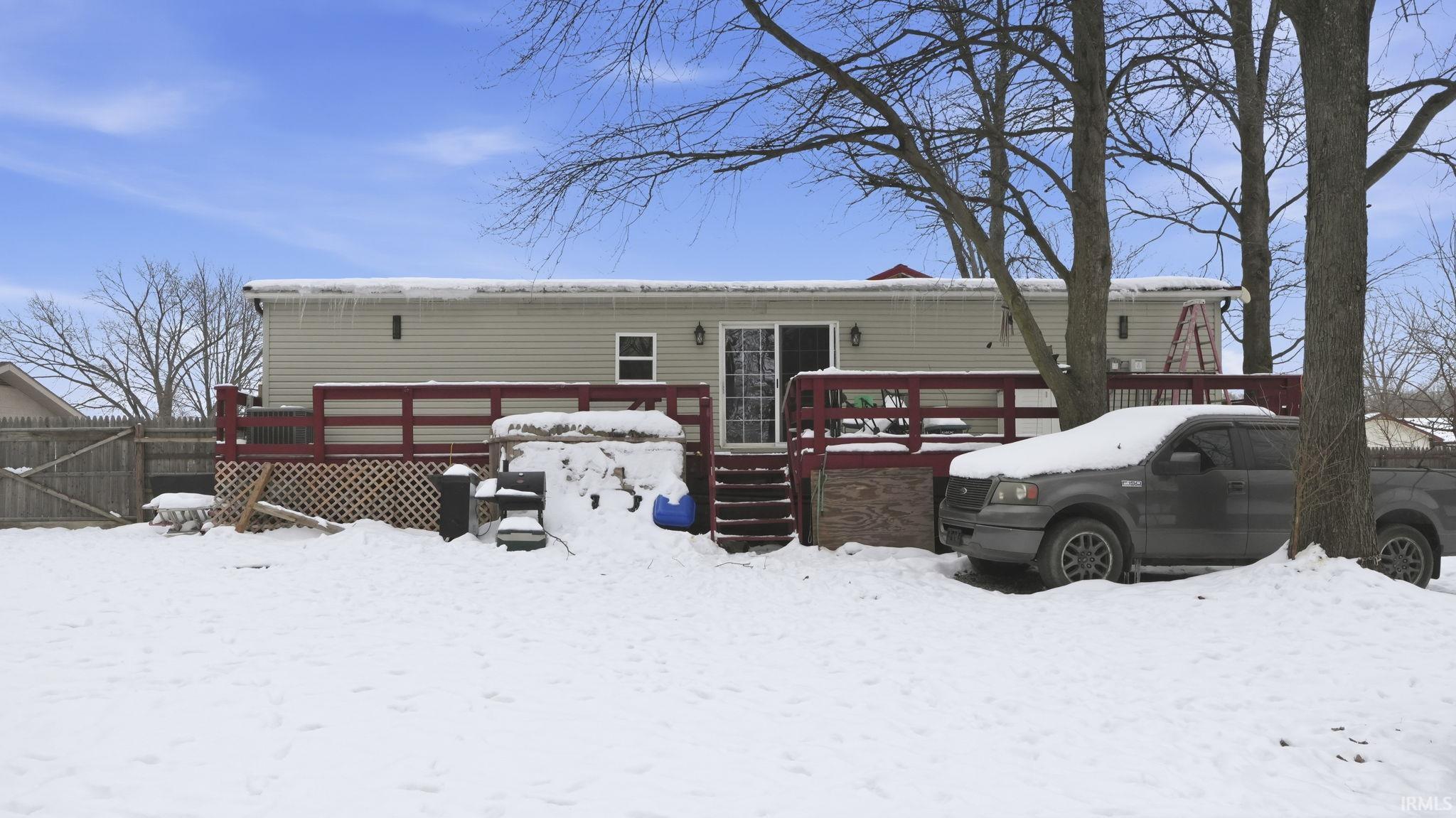 Snow covered rear of property featuring a deck