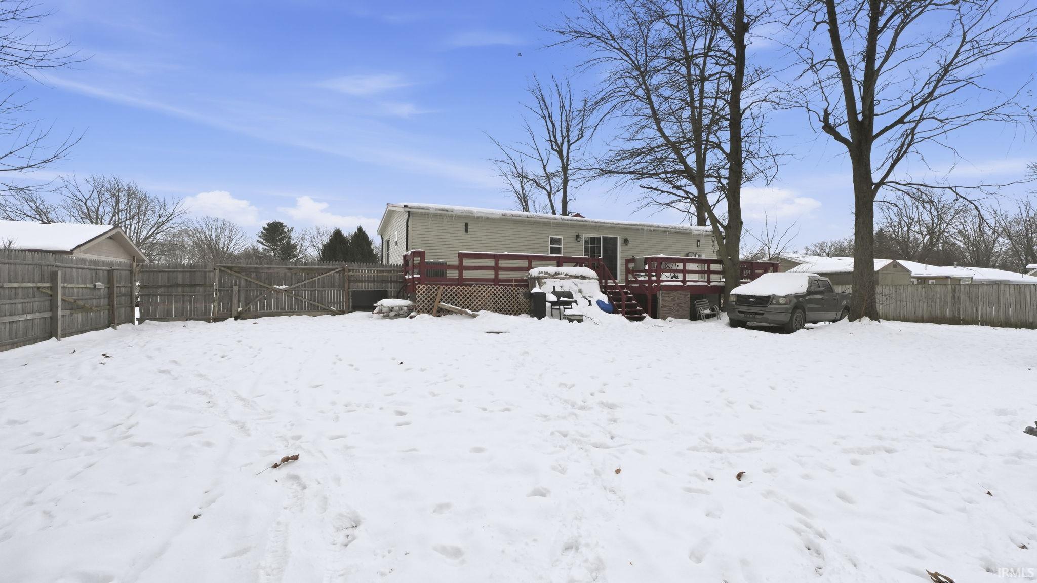 Snow covered house featuring a fenced backyard and a wooden deck